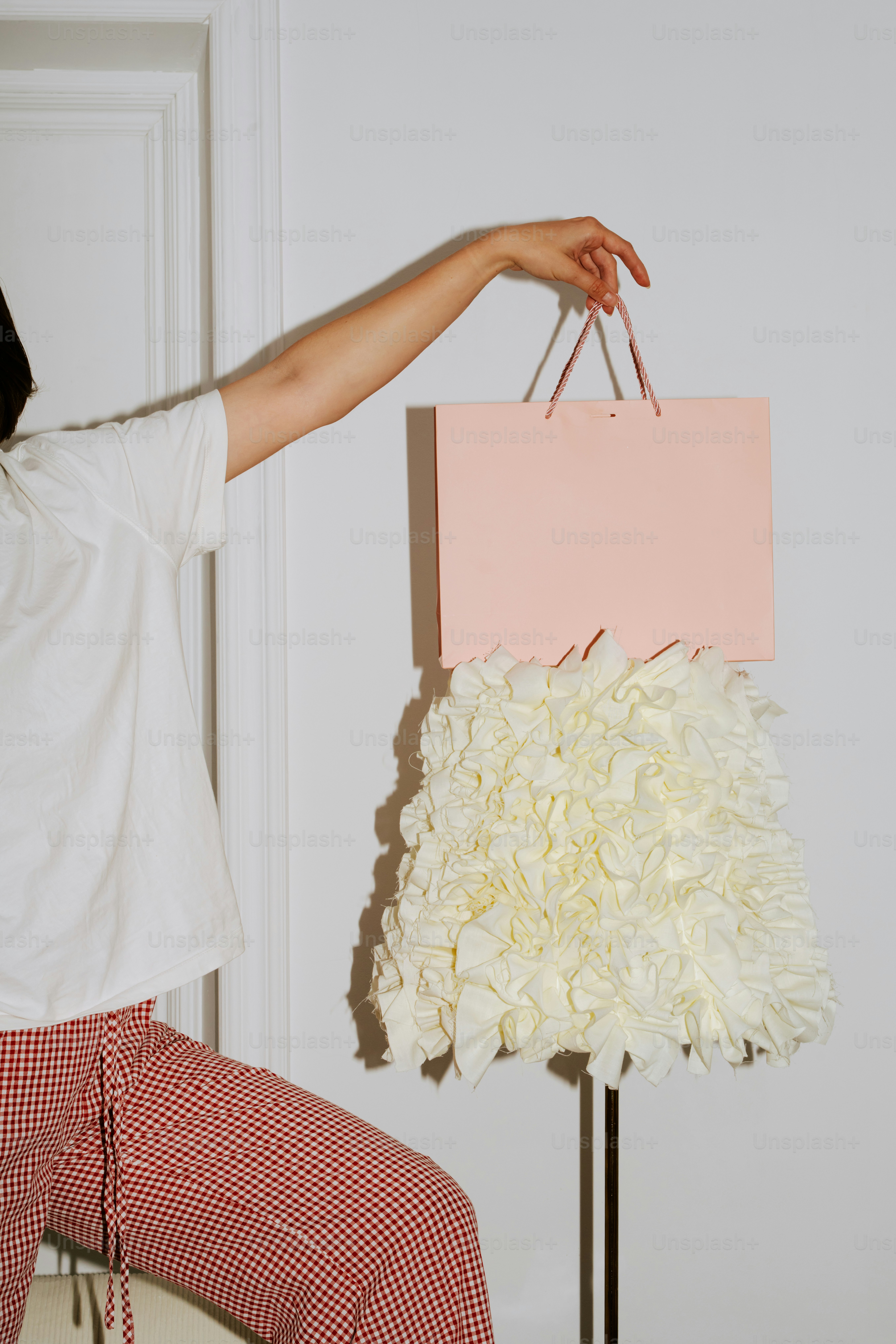 Woman holding a pink shopping bag with ruffled skirt.