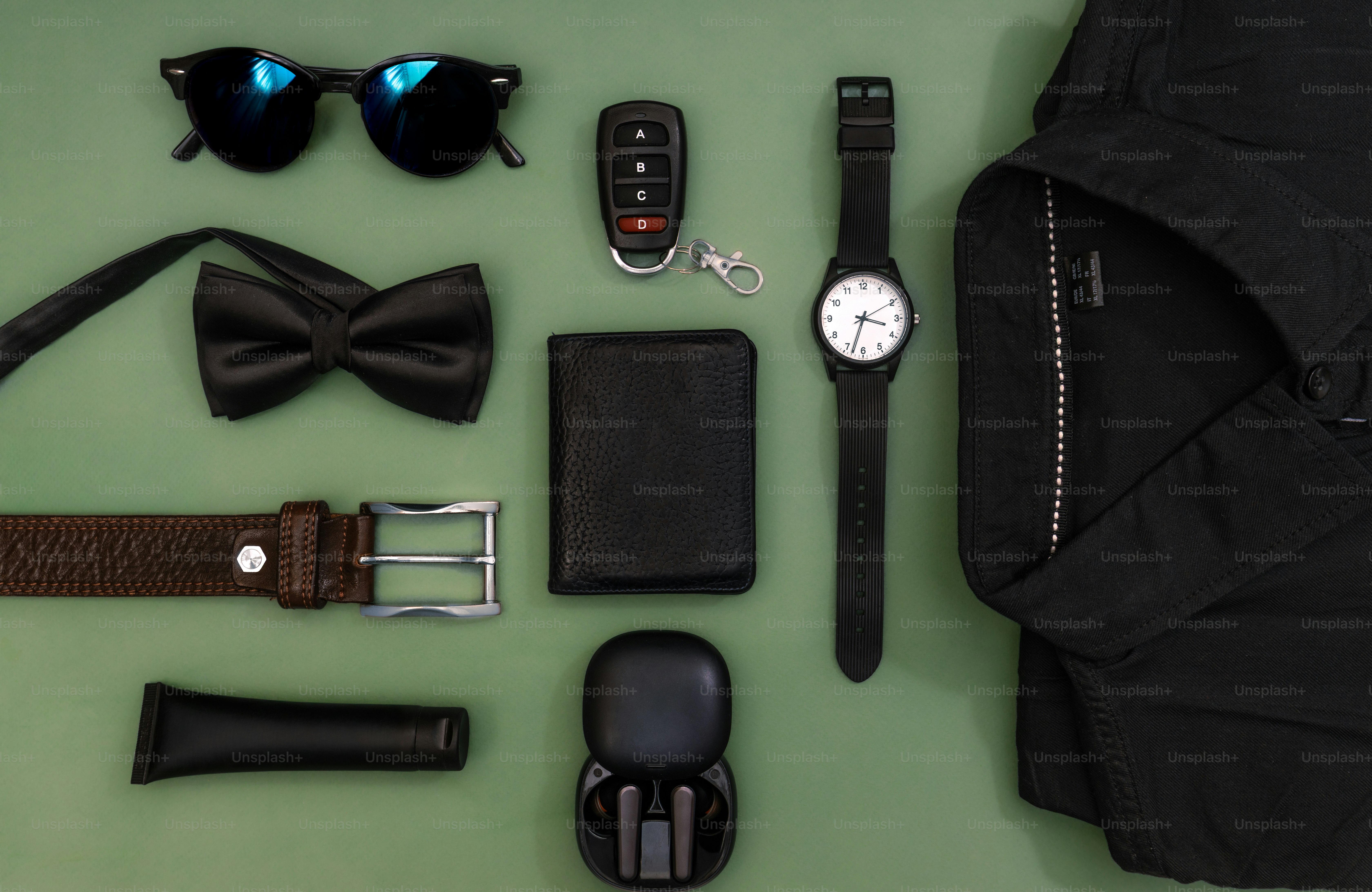 Flat lay of men's accessories and clothing items on green background