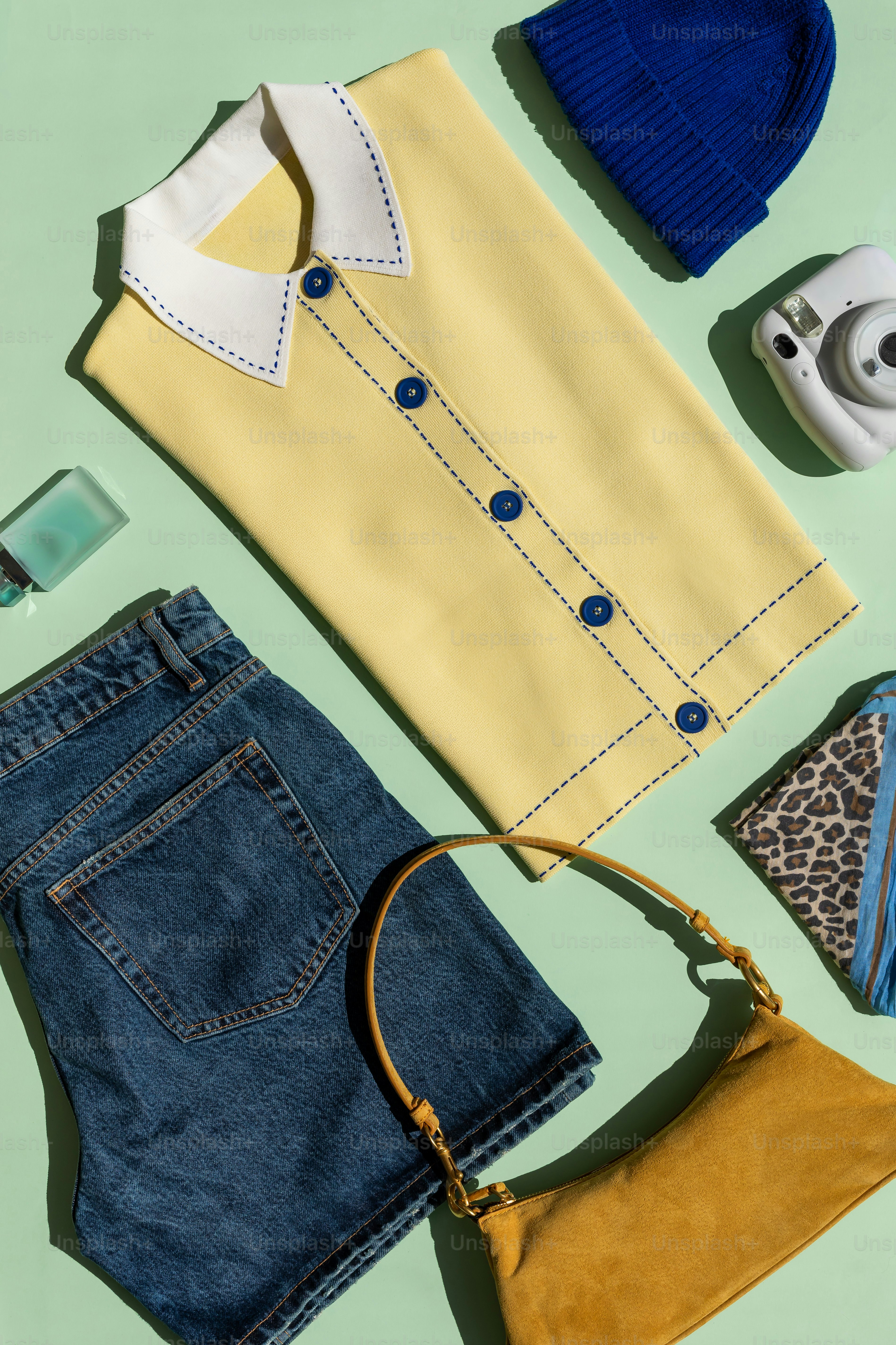 Flat lay of yellow shirt, denim shorts, and accessories.