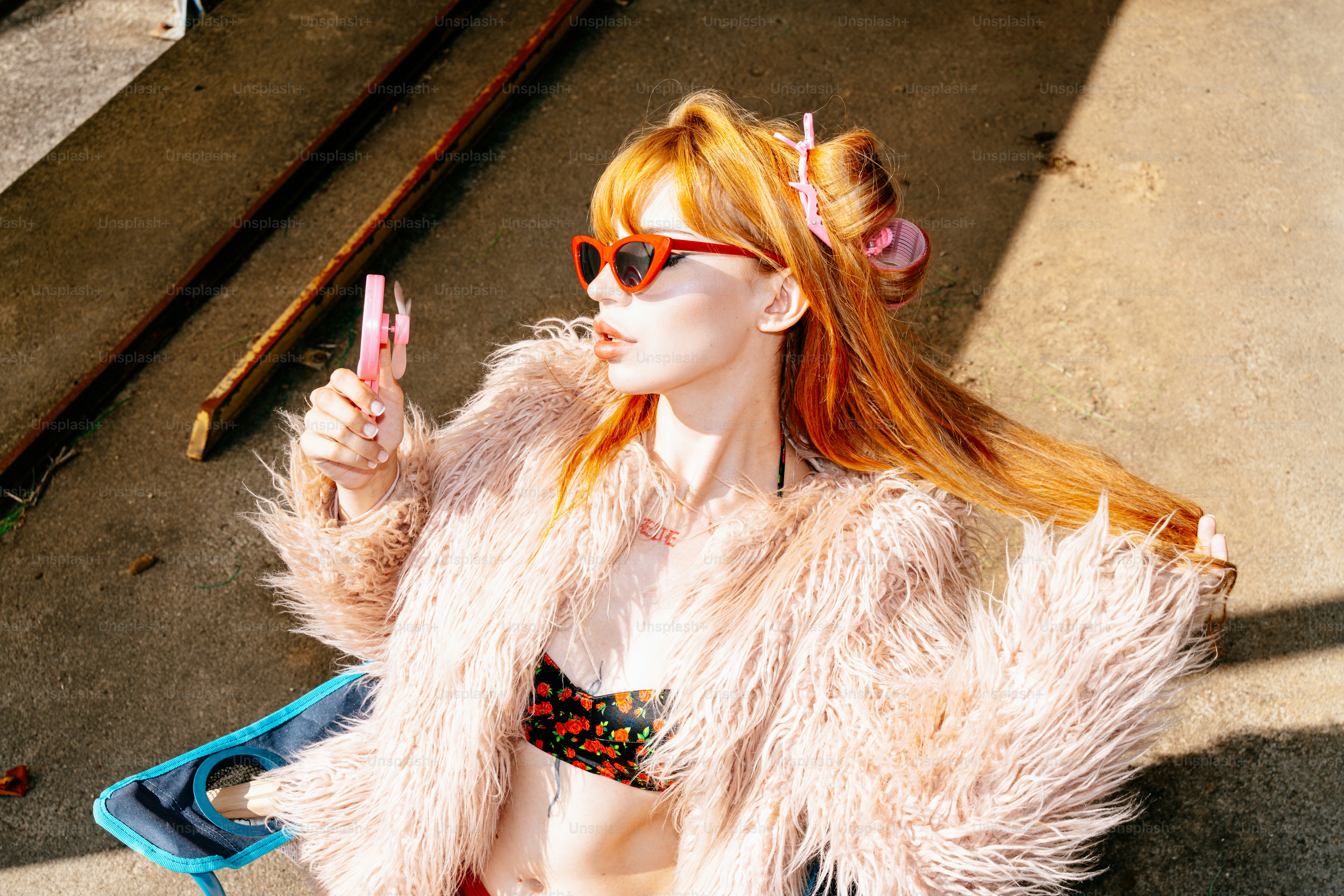 Giovane donna con i capelli rossi che indossa occhiali da sole e cappotto soffice.