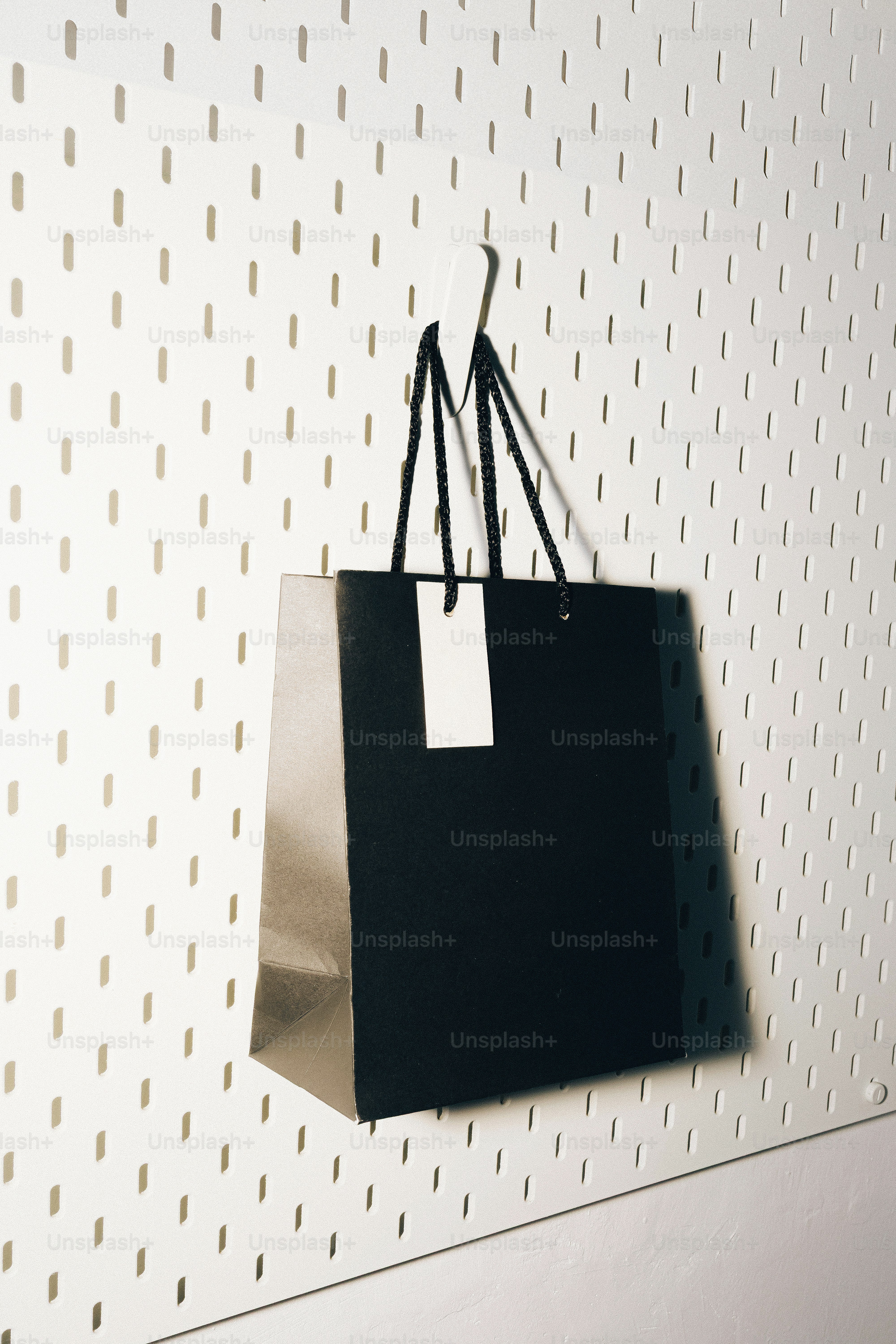 Black shopping bag hanging on a pegboard.