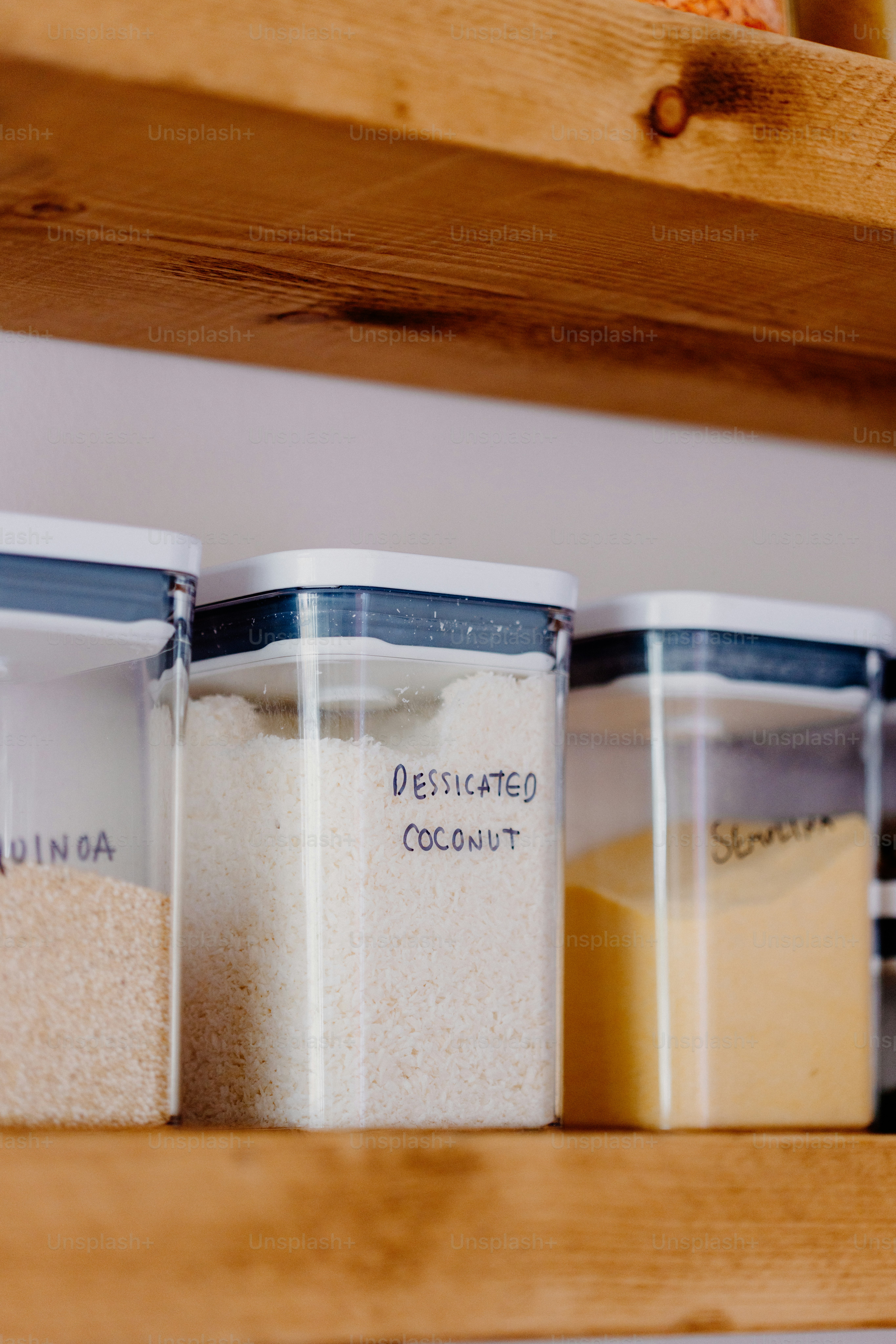 Clear containers with dry goods on a shelf.