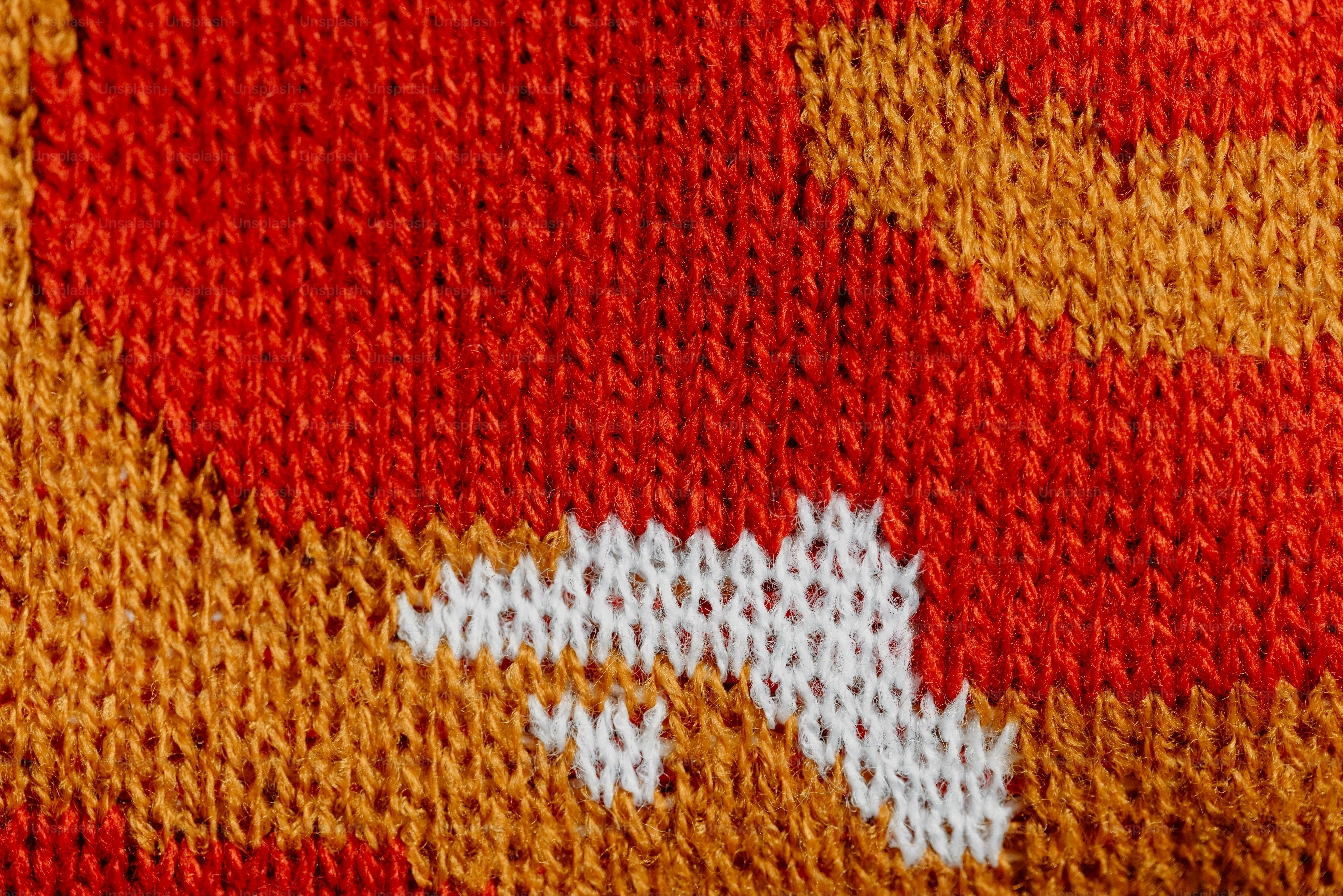 Close-up of a knitted fabric with red and orange patterns.