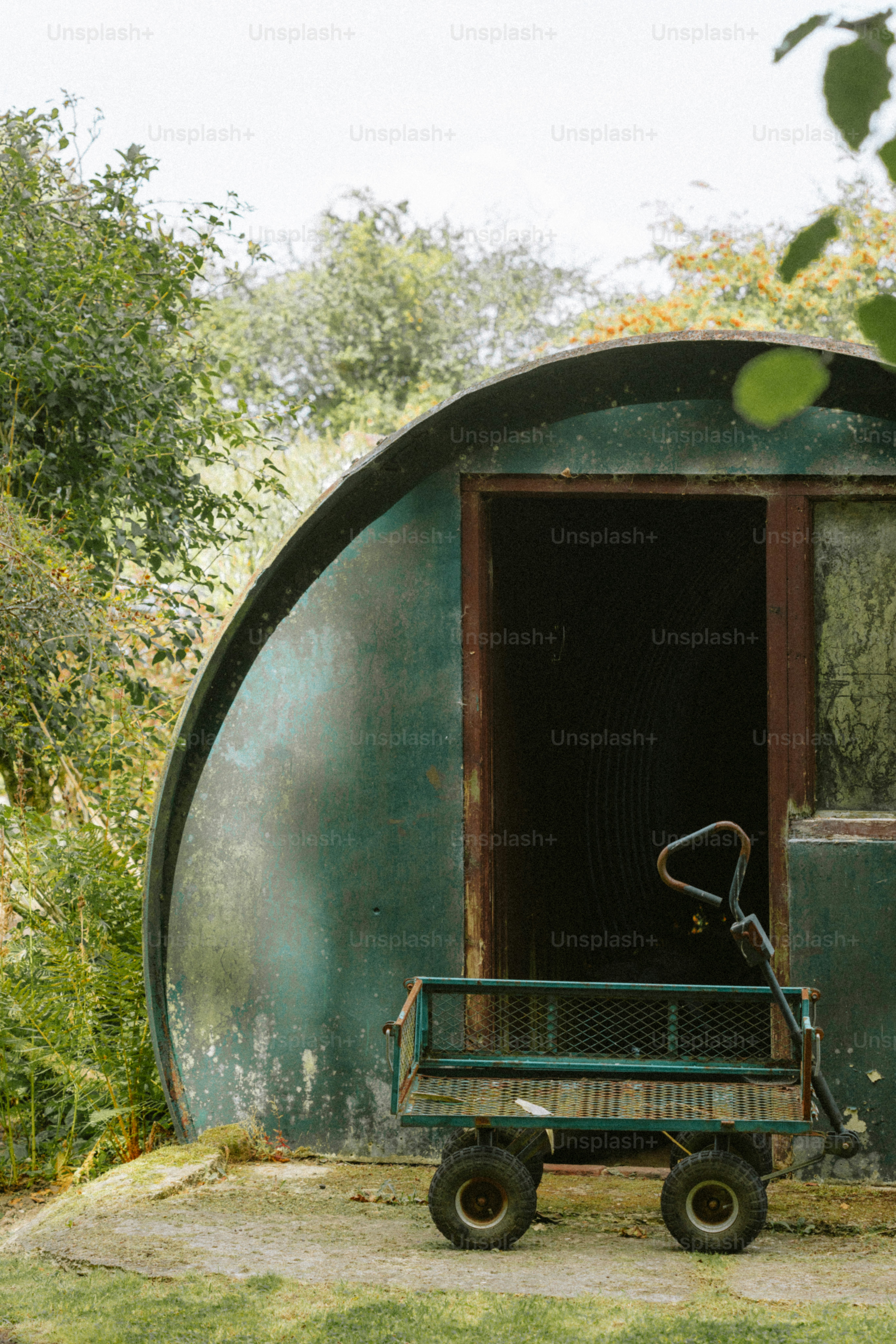 Uma carroça verde desgastada fica do lado de fora de um prédio curvo.