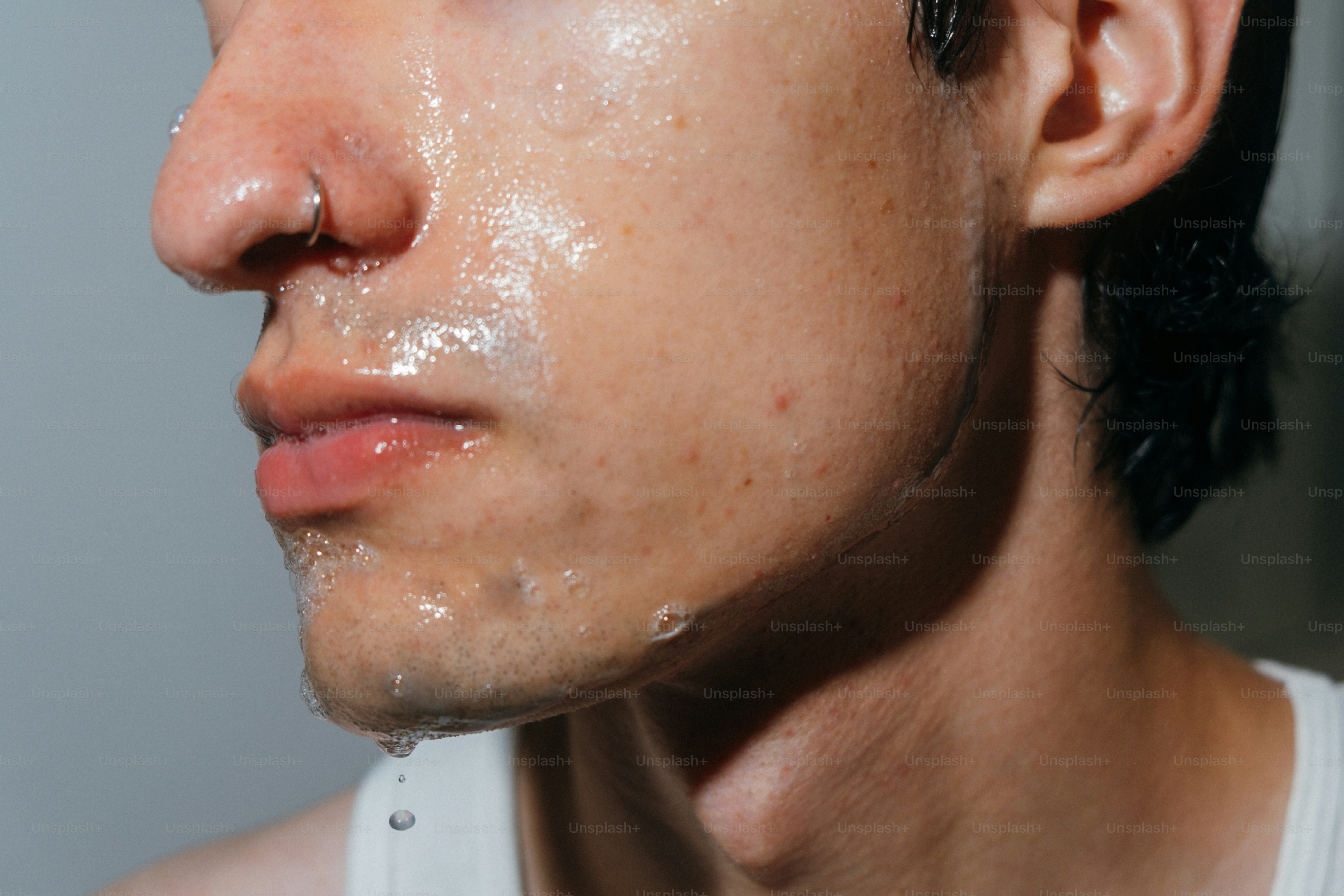Man's face glistening with water droplets.