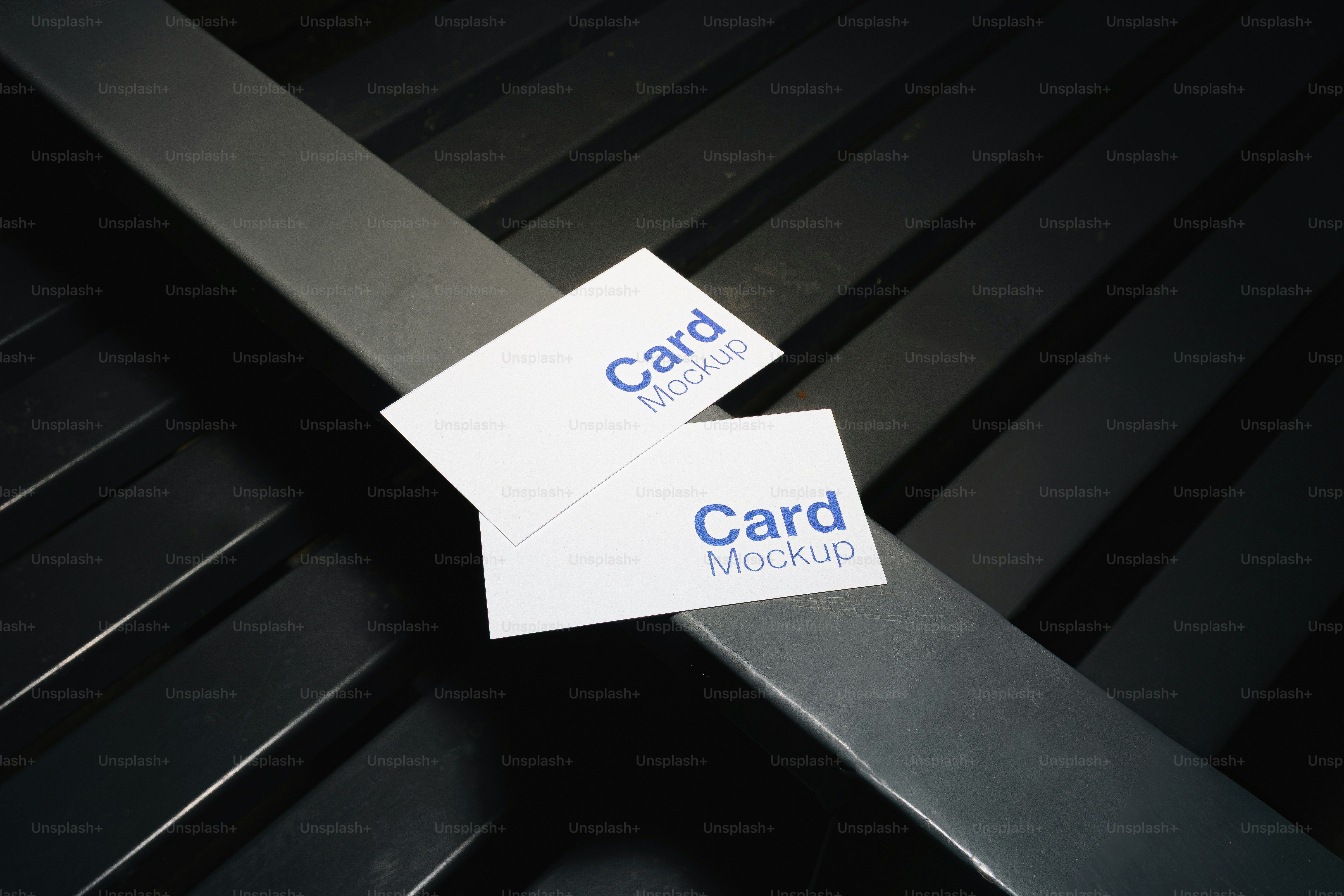 Two white business cards on a dark background.
