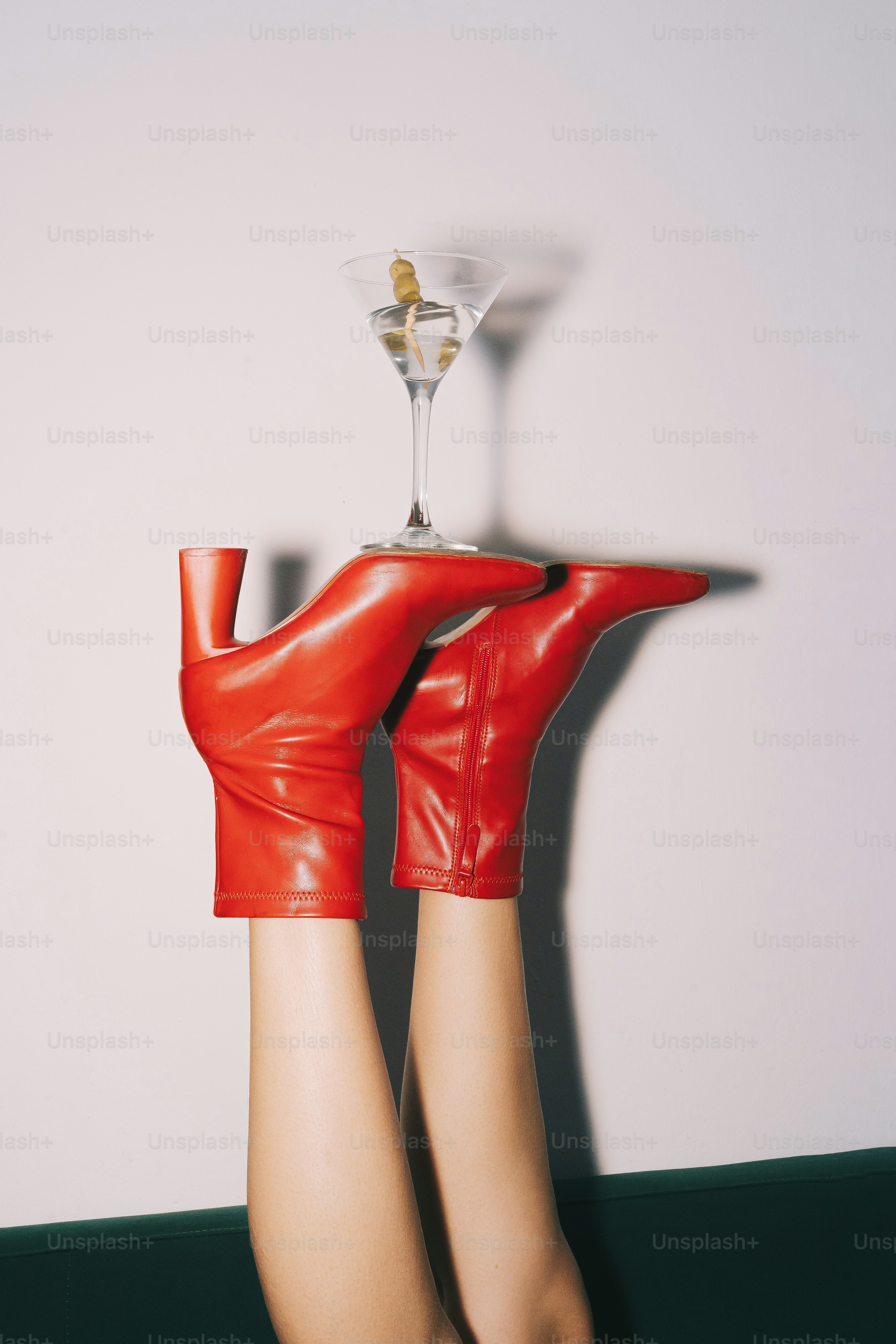 Sepatu bot merah menyeimbangkan gelas martini di kaki