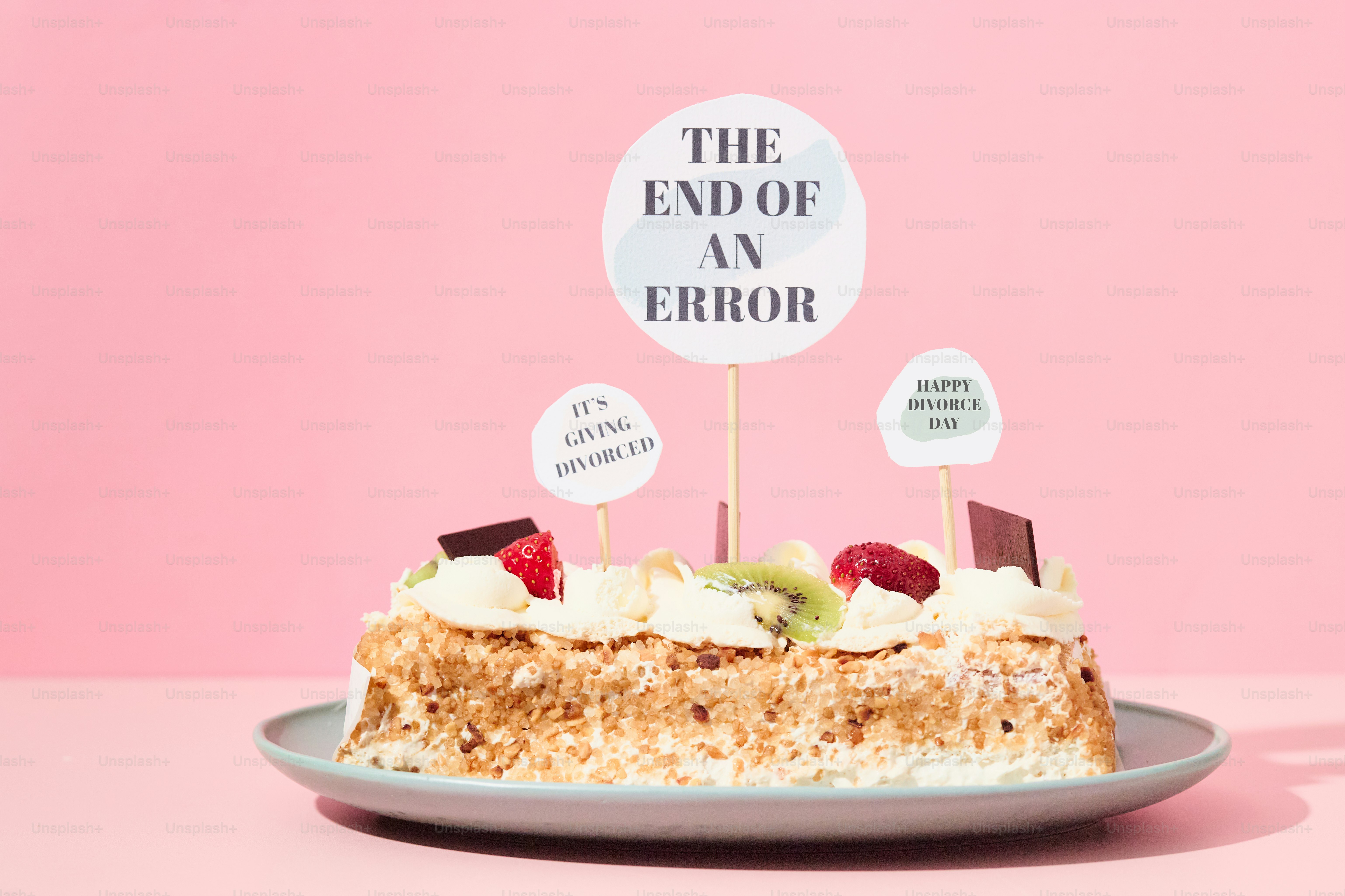 A cake decorated with humorous toppers reading “The End of Error” on a pink background.