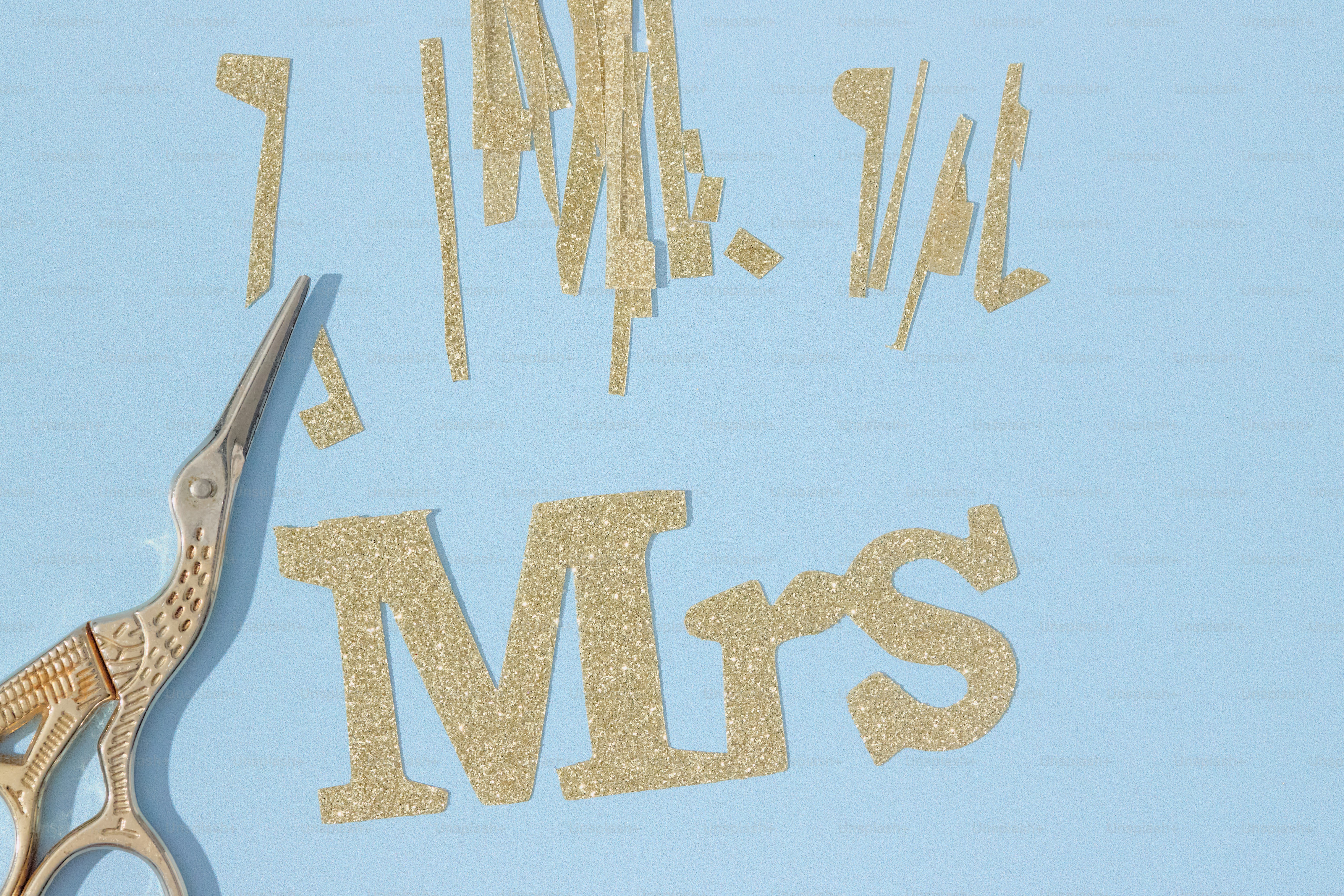 Ciseaux coupant des lettres scintillantes d’or épelant « mme ».