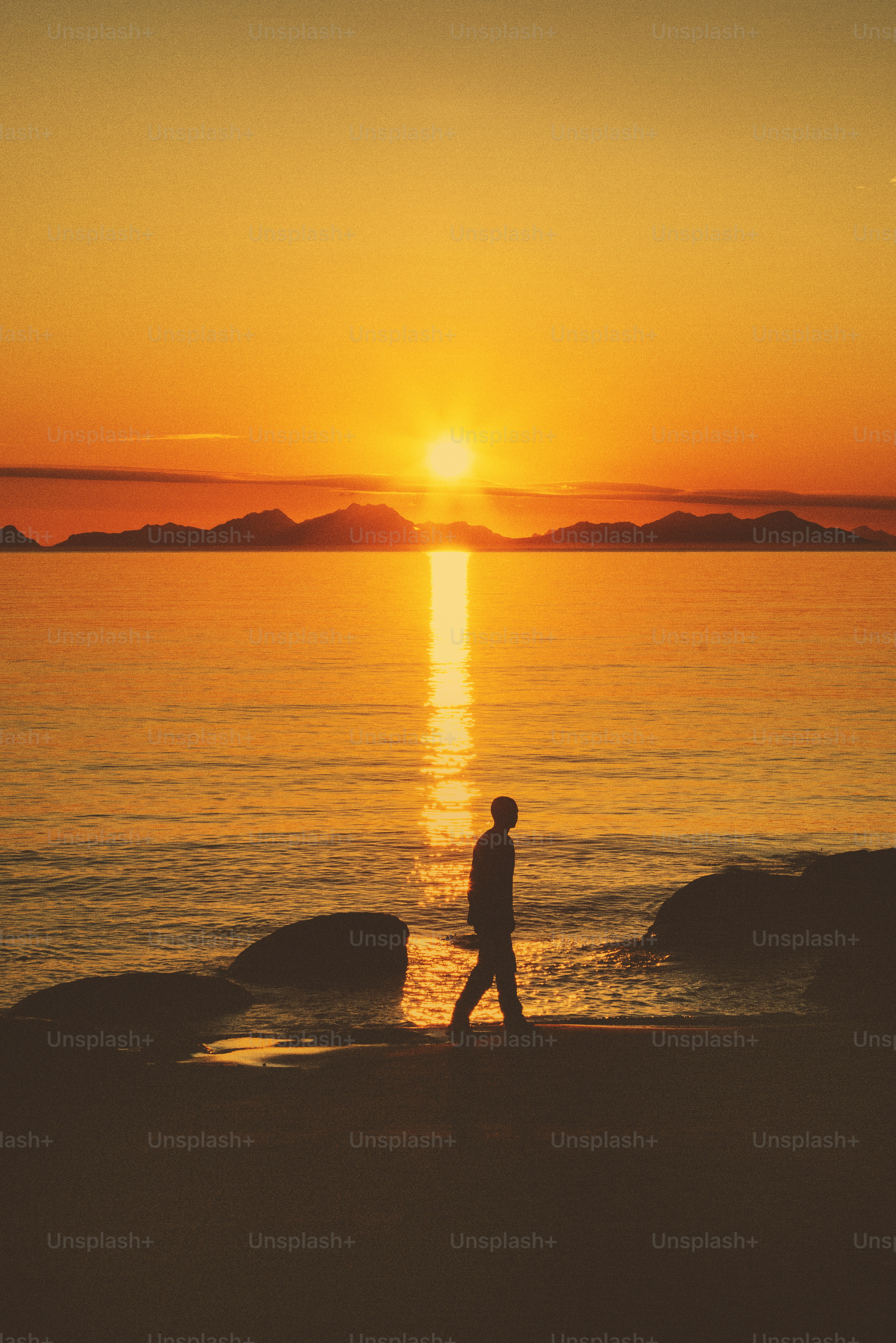 An image of a man walking on beach during sunset