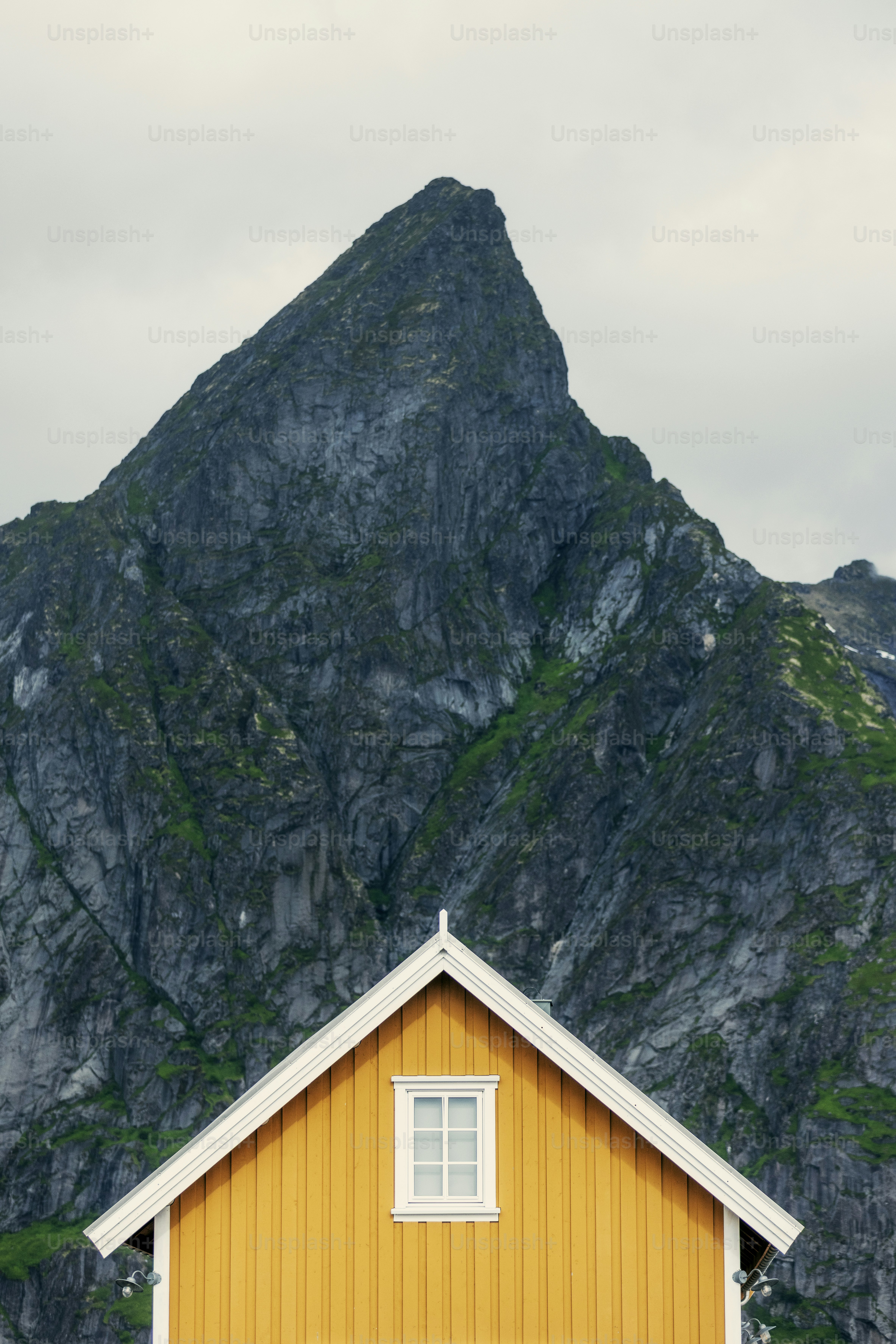 Yellow house roof against a rocky mountain backdrop.