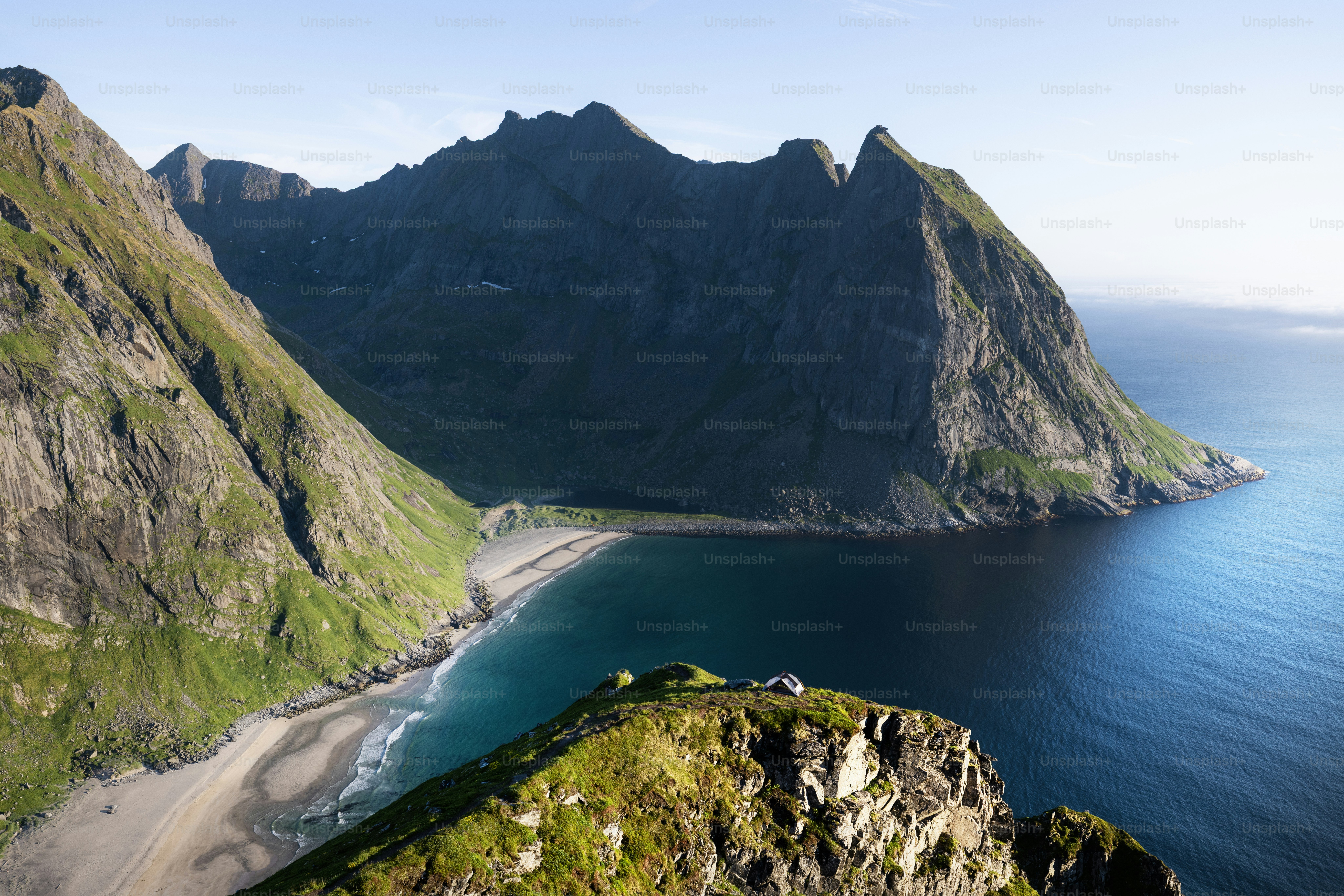 Rugged mountains meet the ocean with a sandy beach.