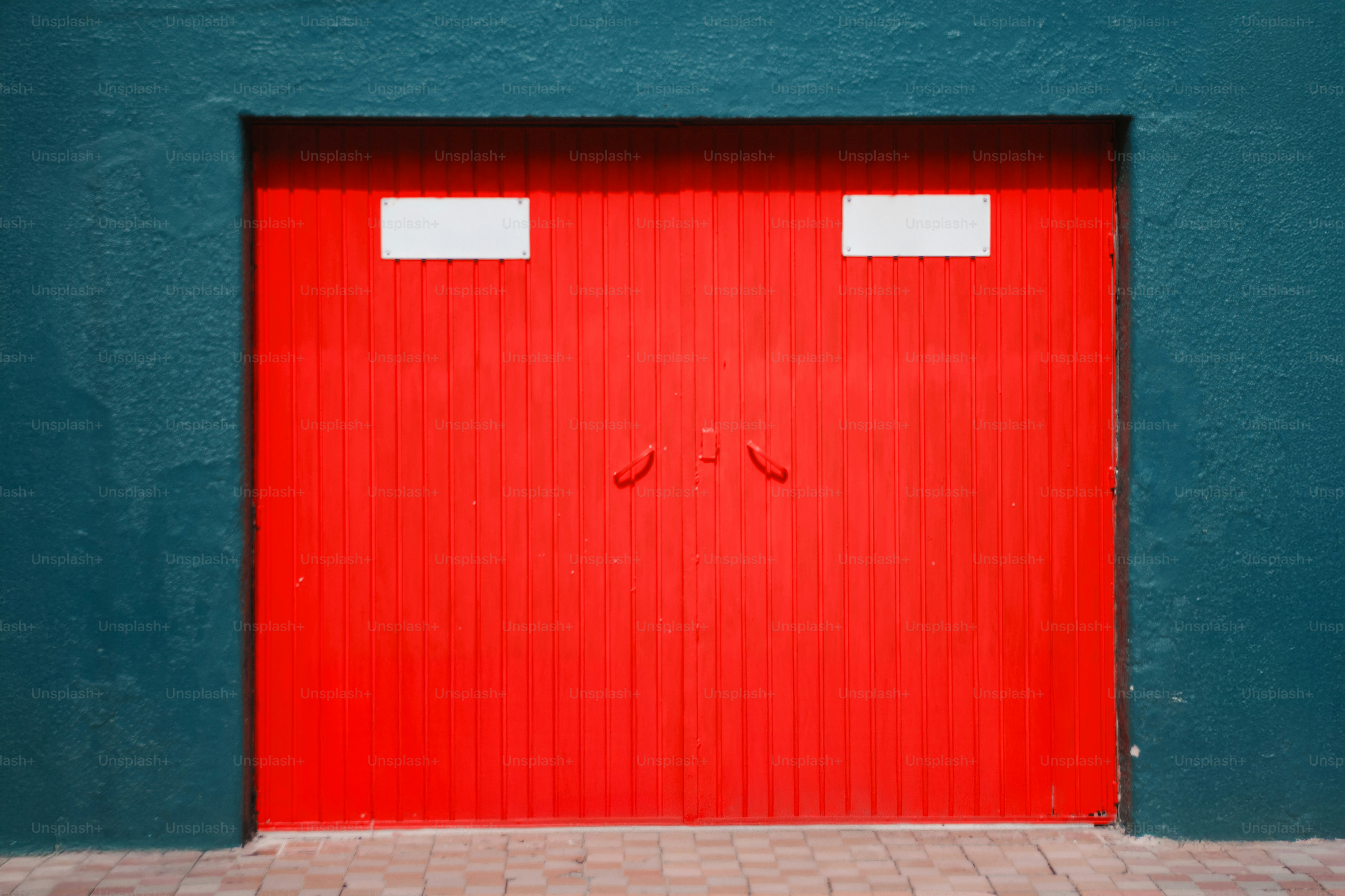 Doppie porte rosso brillante incastonate in parete verde acqua