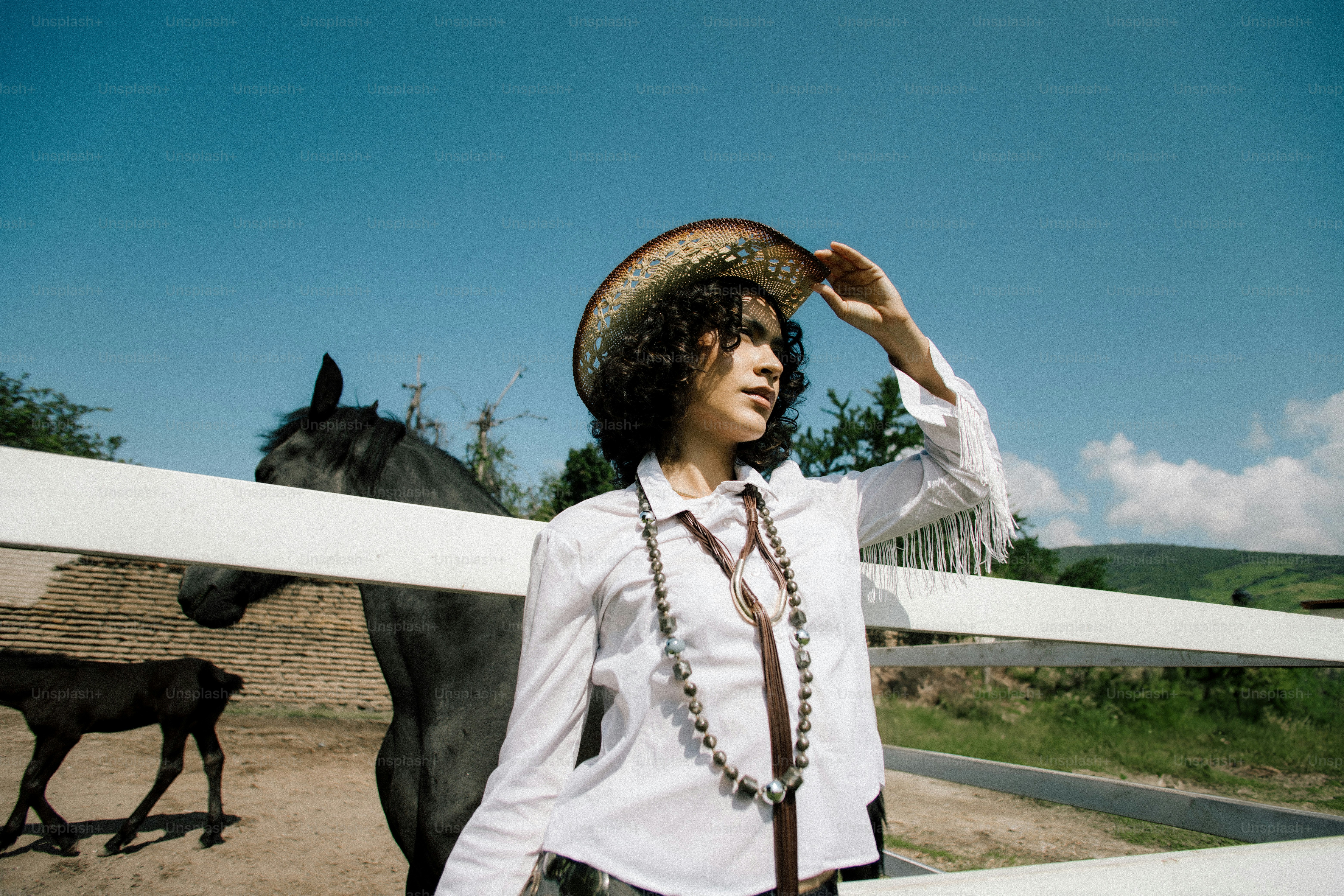 Woman in cowboy hat with horse on sunny day