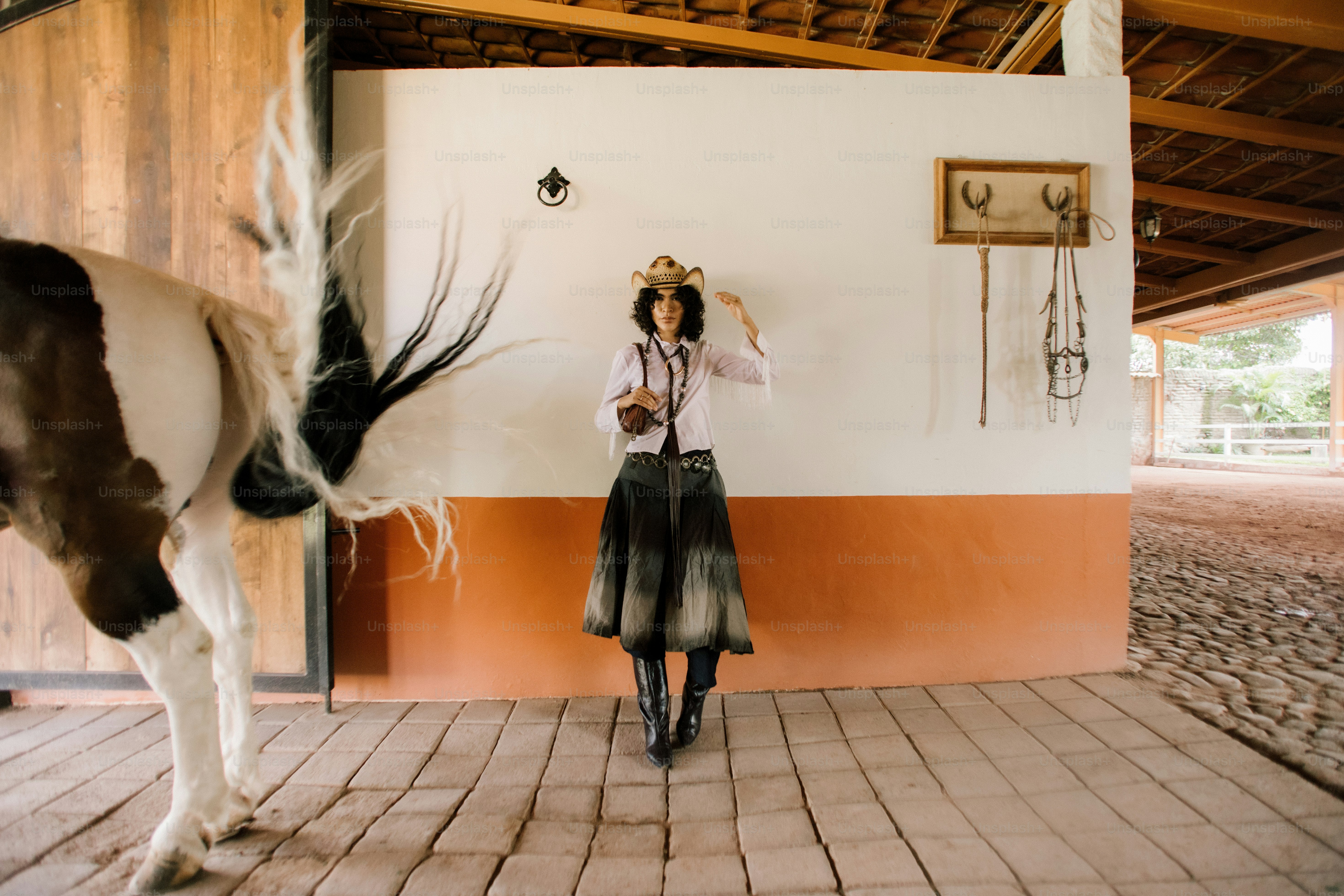 Cowgirl posiert mit einem Pferd in einem Stall.