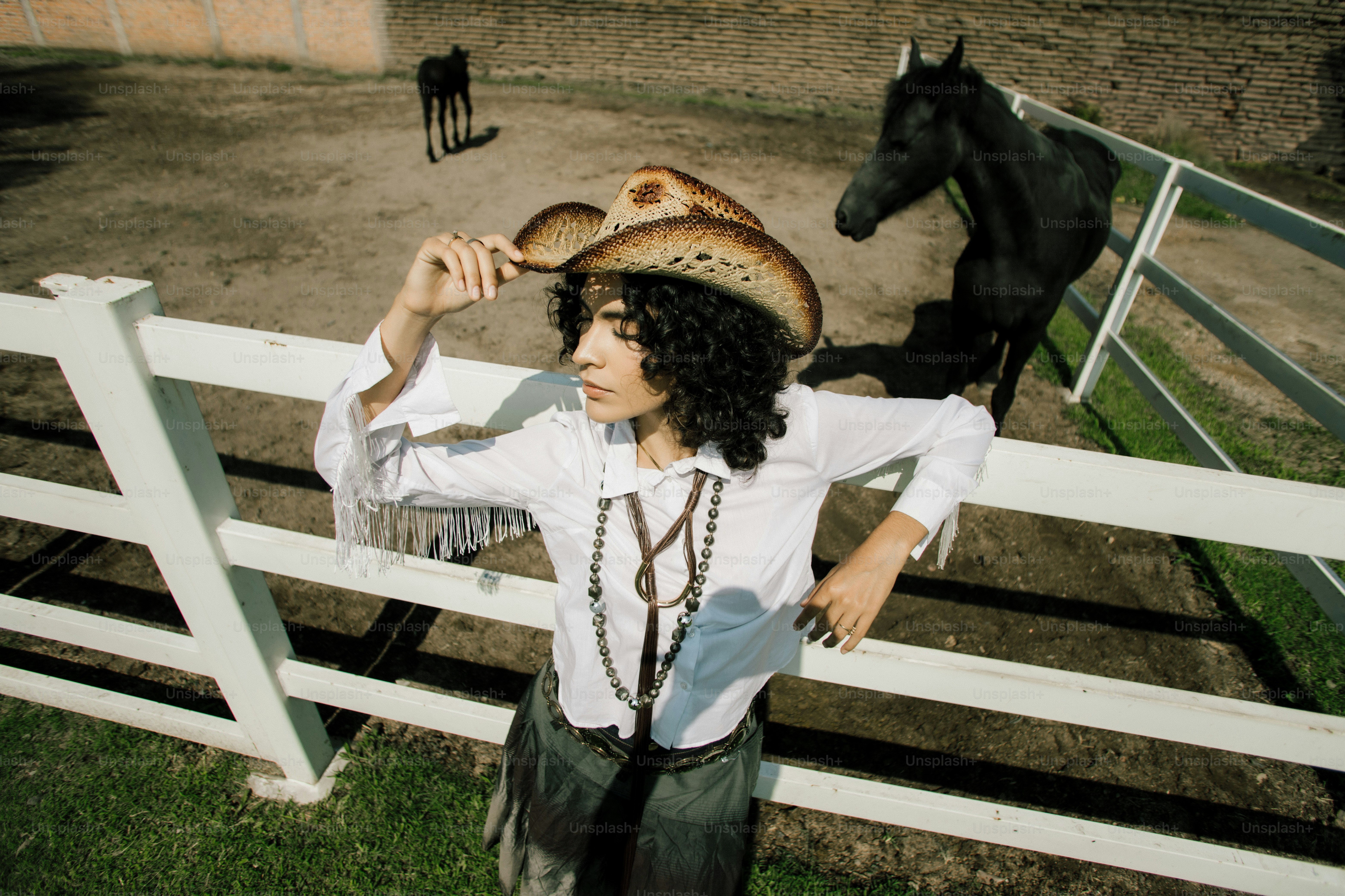 Woman in cowboy hat near horses on ranch