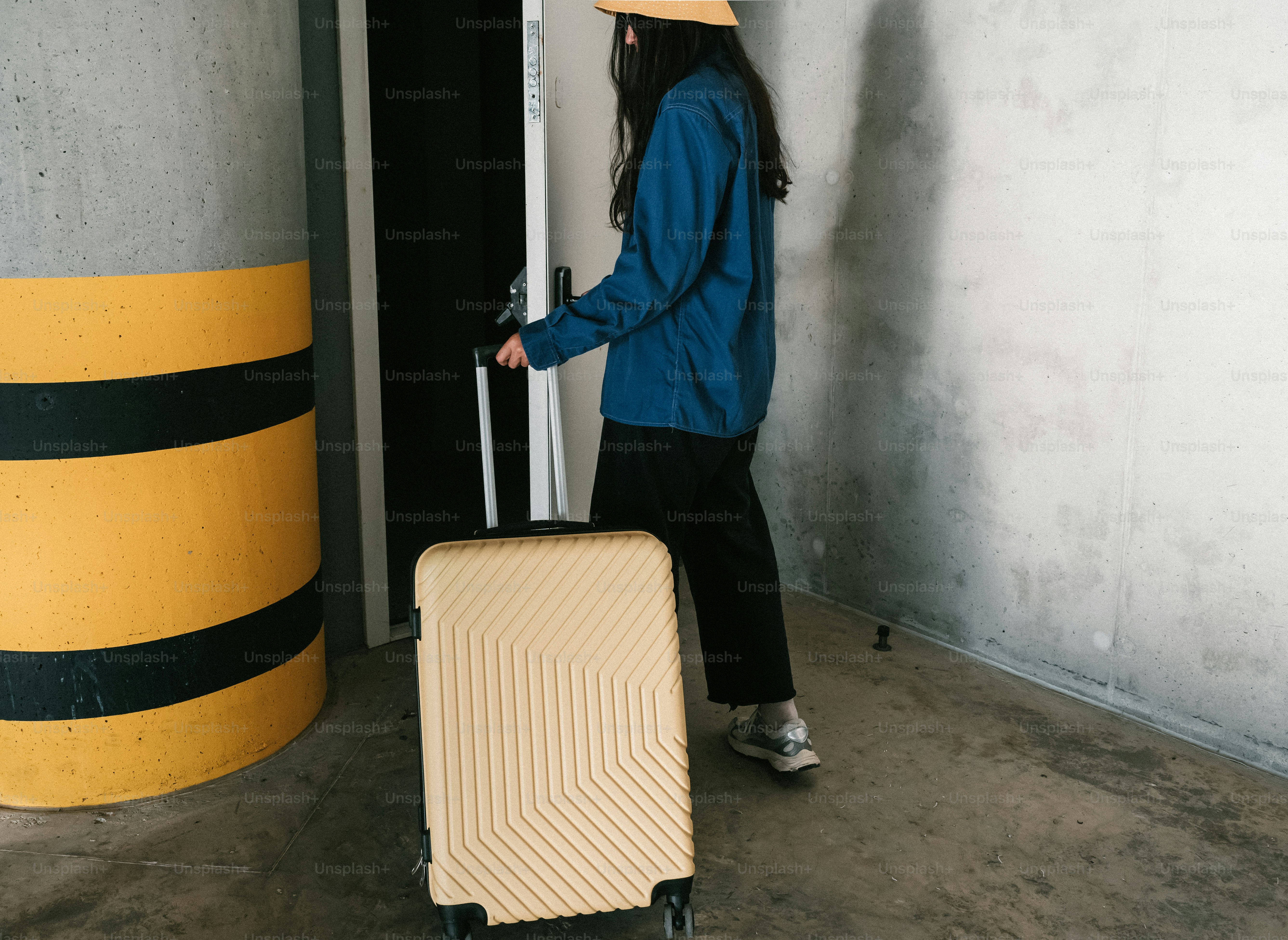 Woman with suitcase opening door in parking garage.