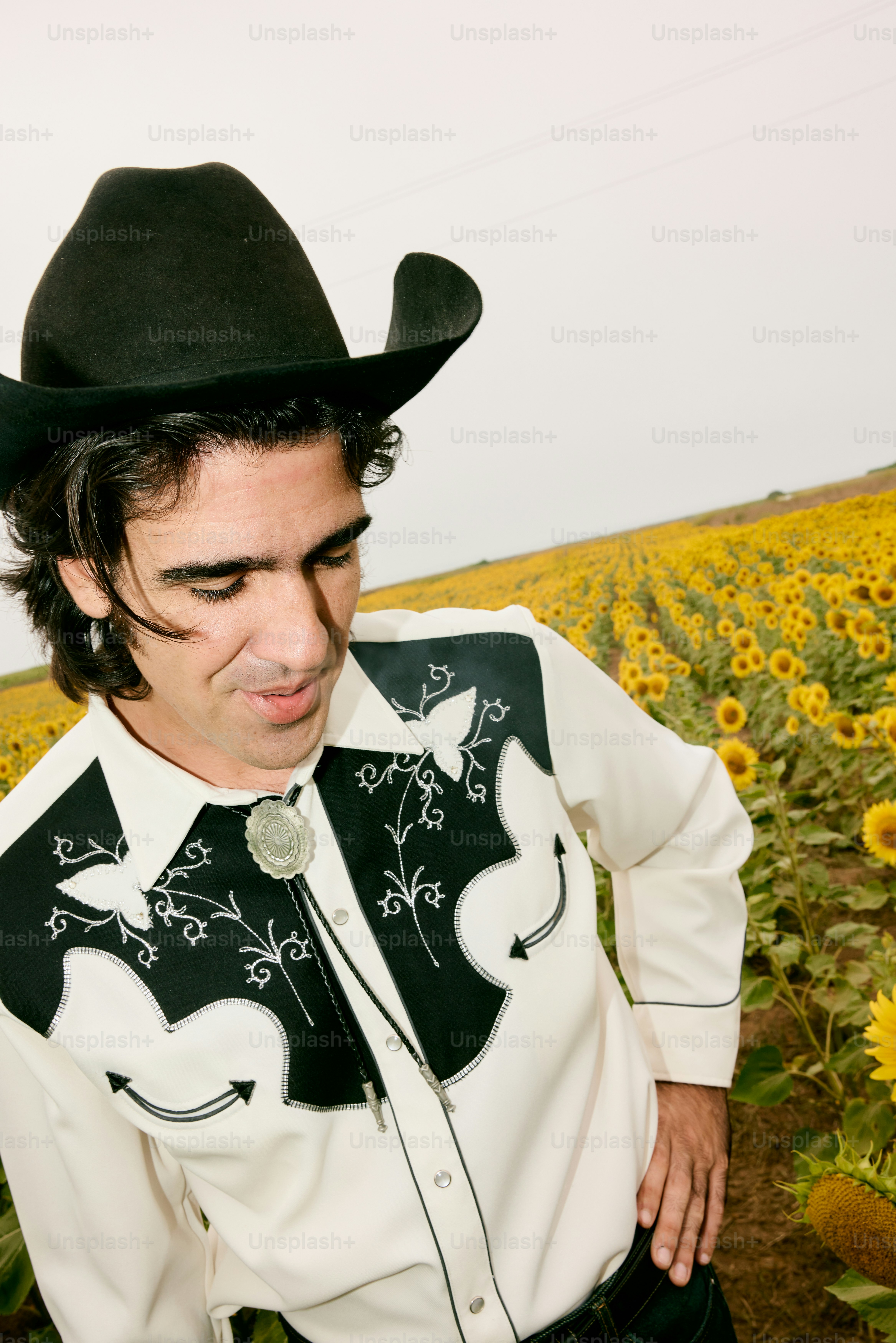 Mann mit Cowboyhut und Hemd im Sonnenblumenfeld
