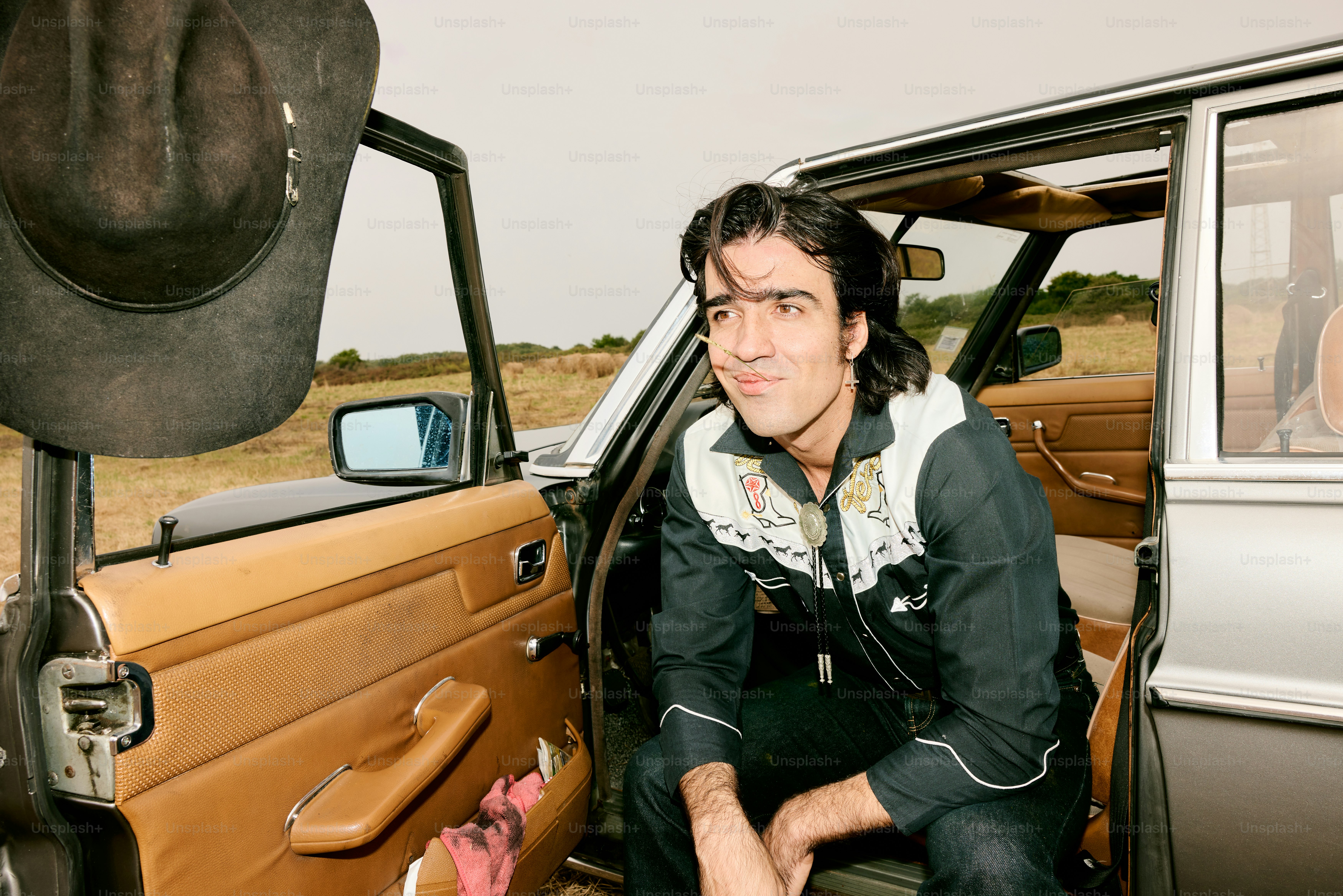 Man in cowboy attire sits in car door