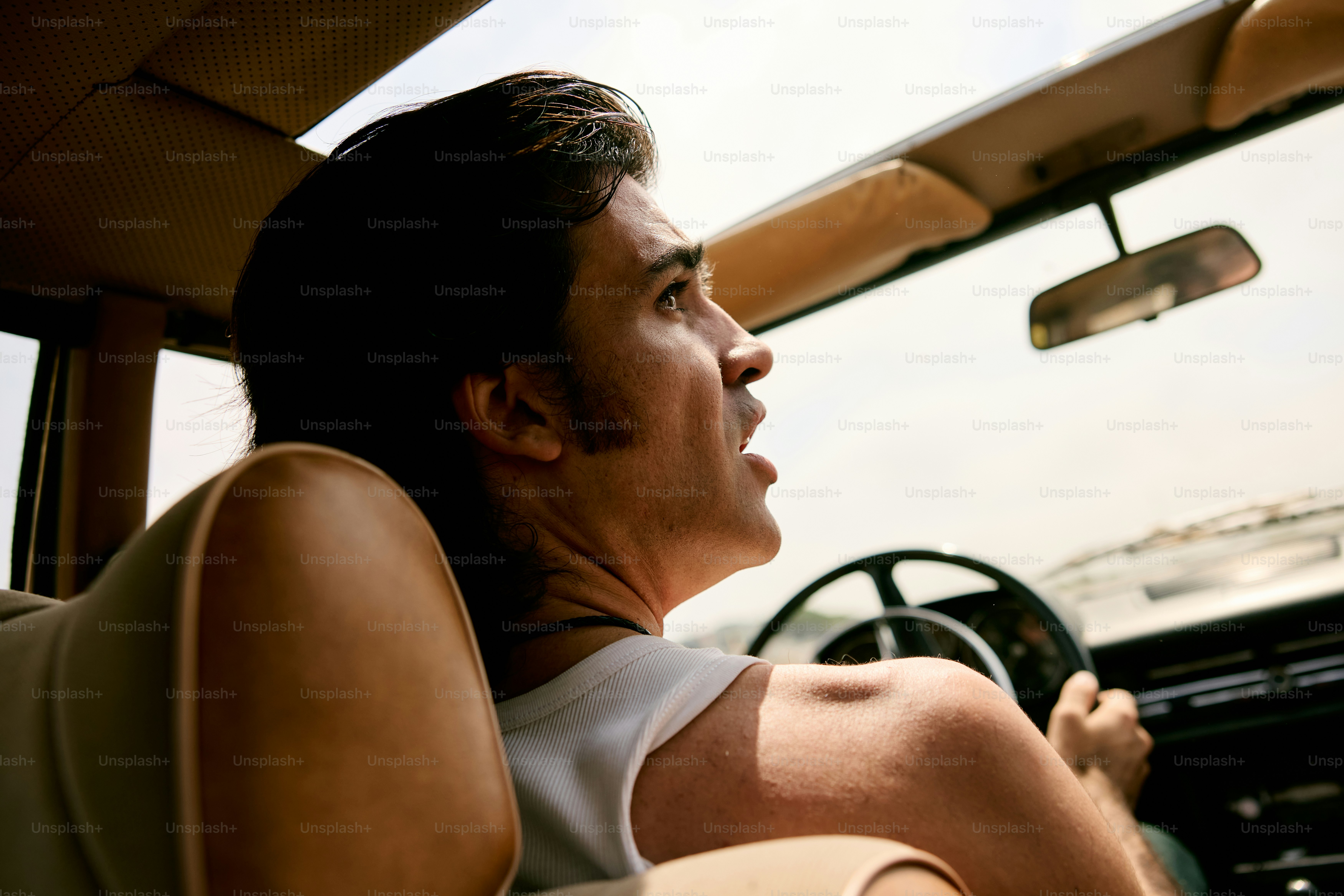 Man driving a car looking upwards with surprise.