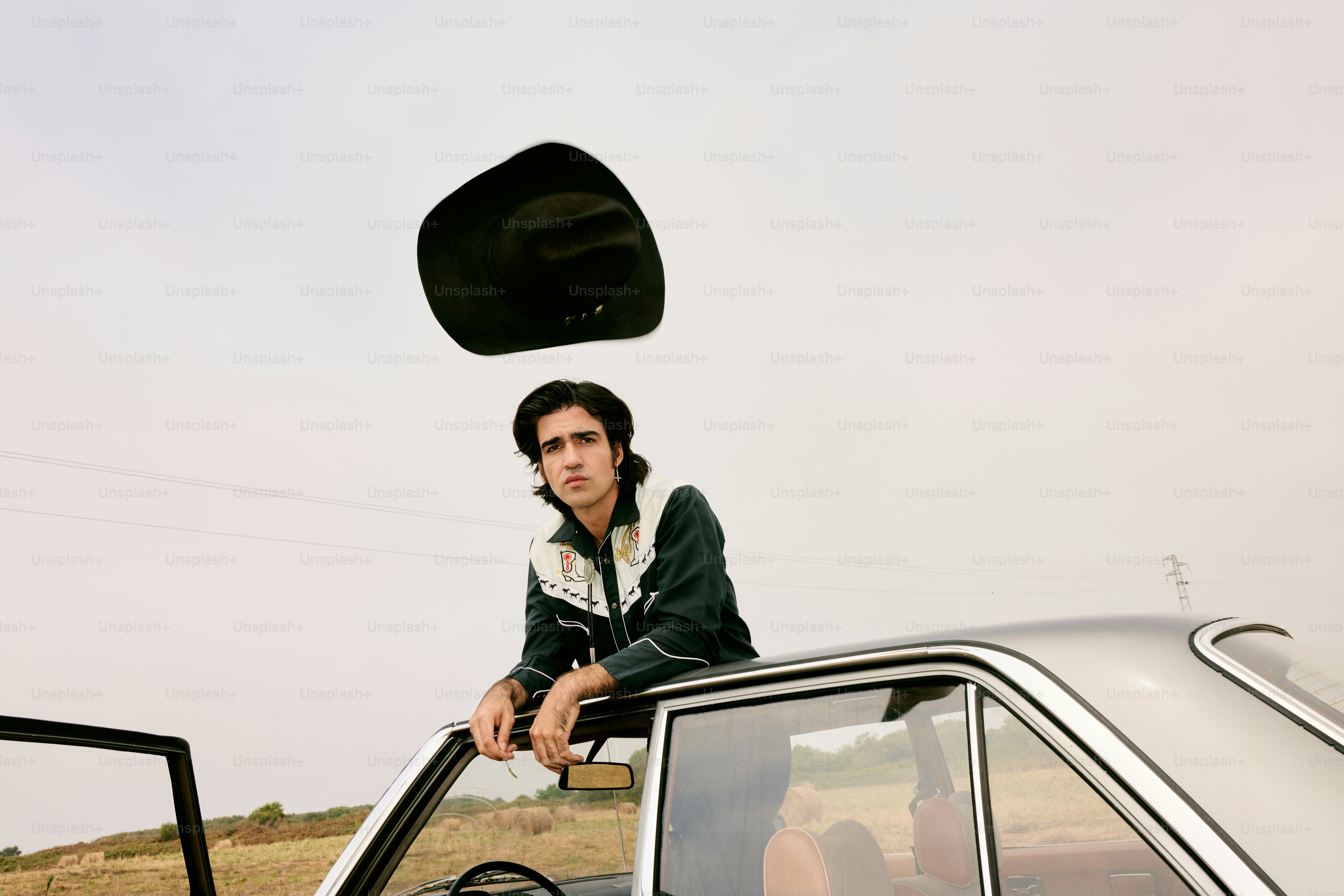 Man in cowboy hat by car outdoors