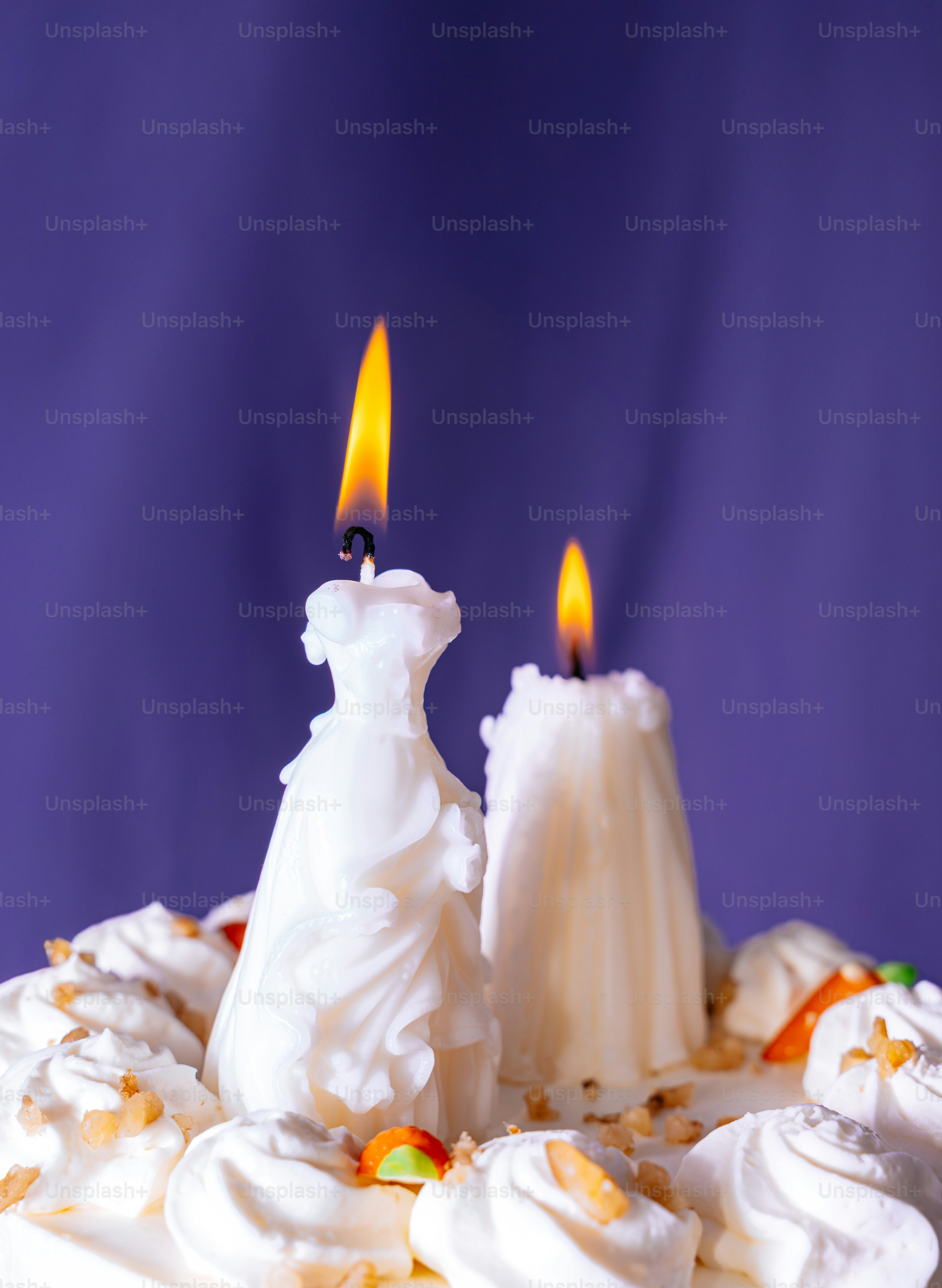 Two lit candles on a cake with frosting.