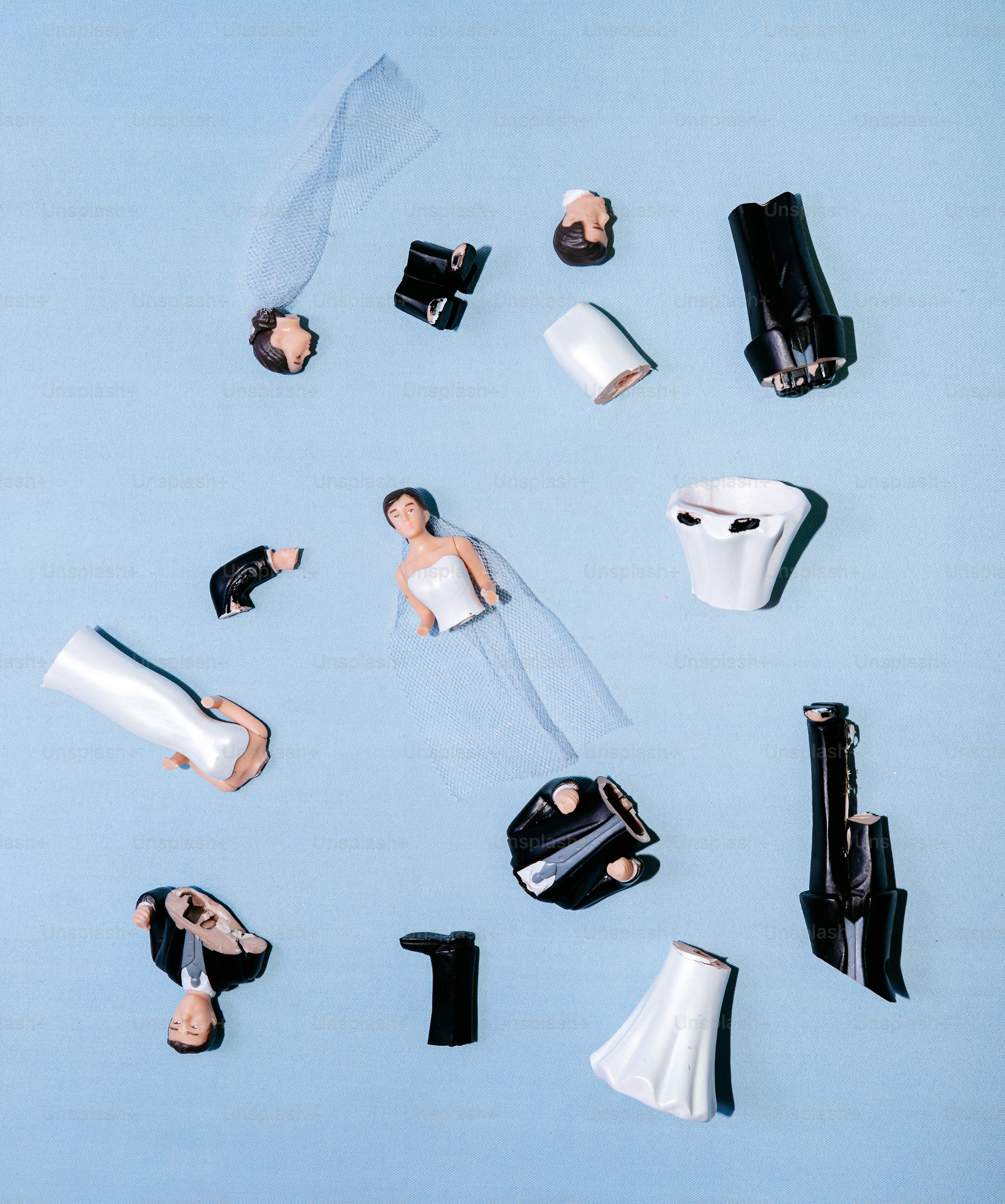 Broken wedding cake toppers scattered on blue background