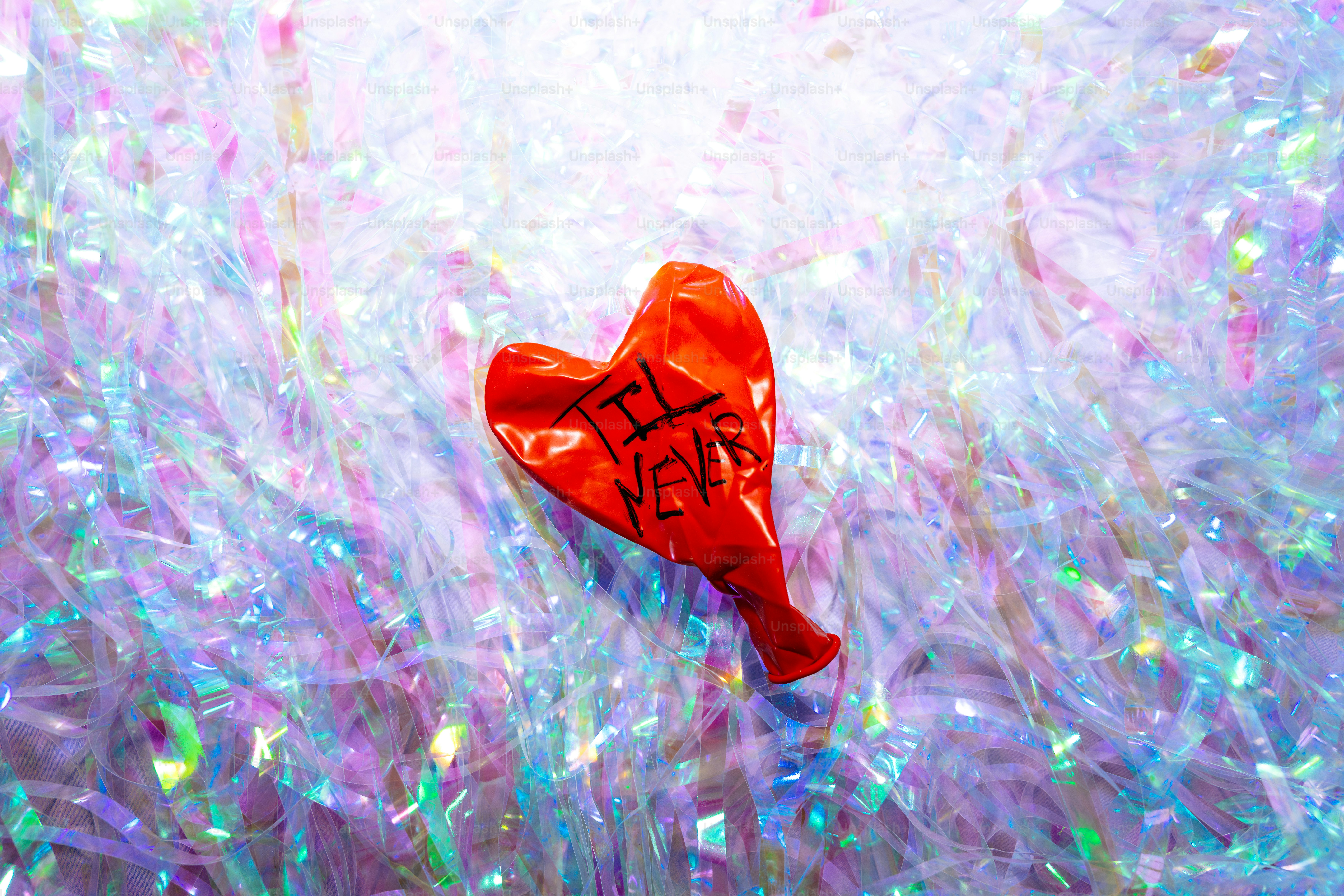 A deflated red heart-shaped balloon with writing.