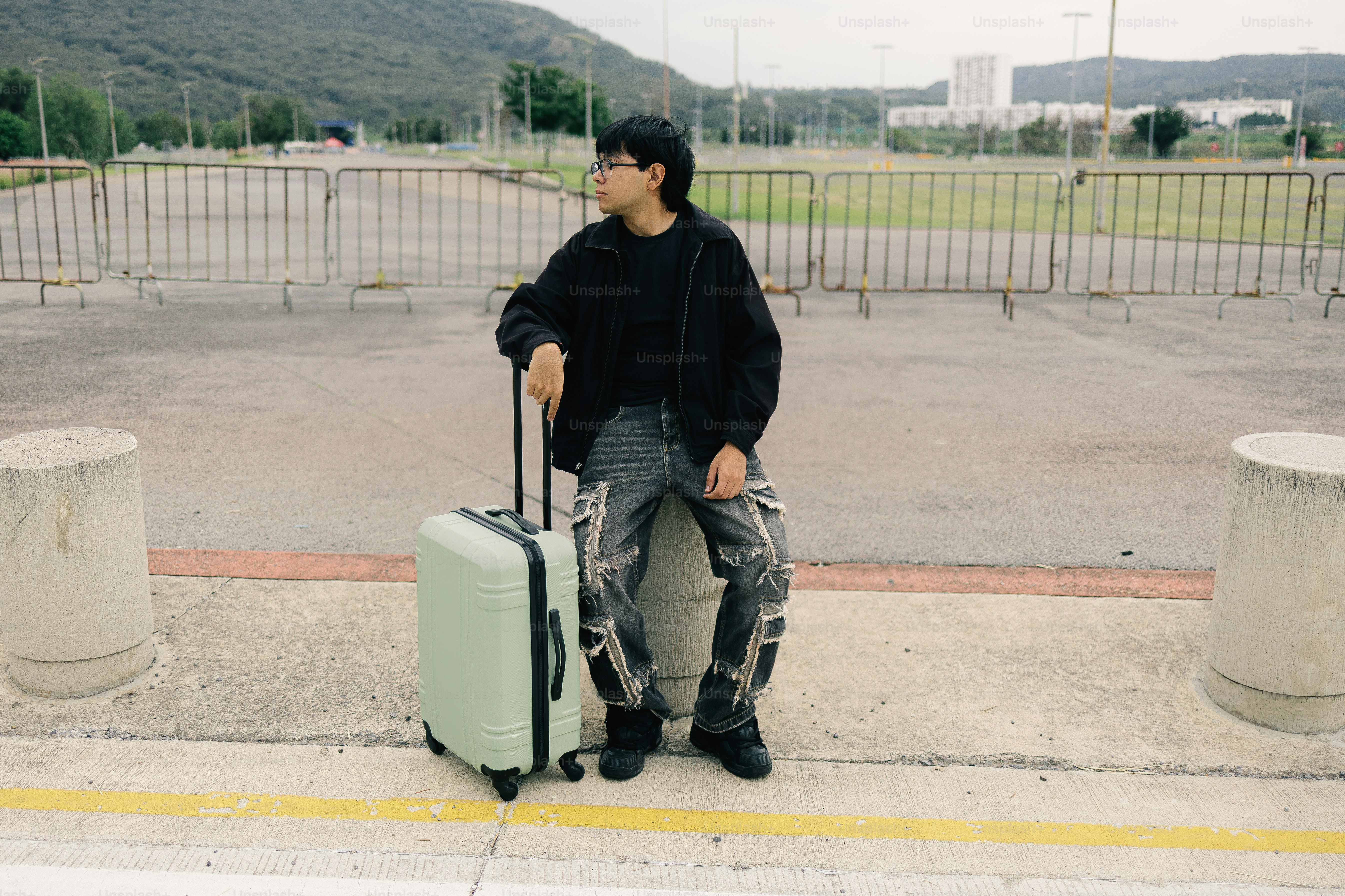 Young person with suitcase waiting outdoors