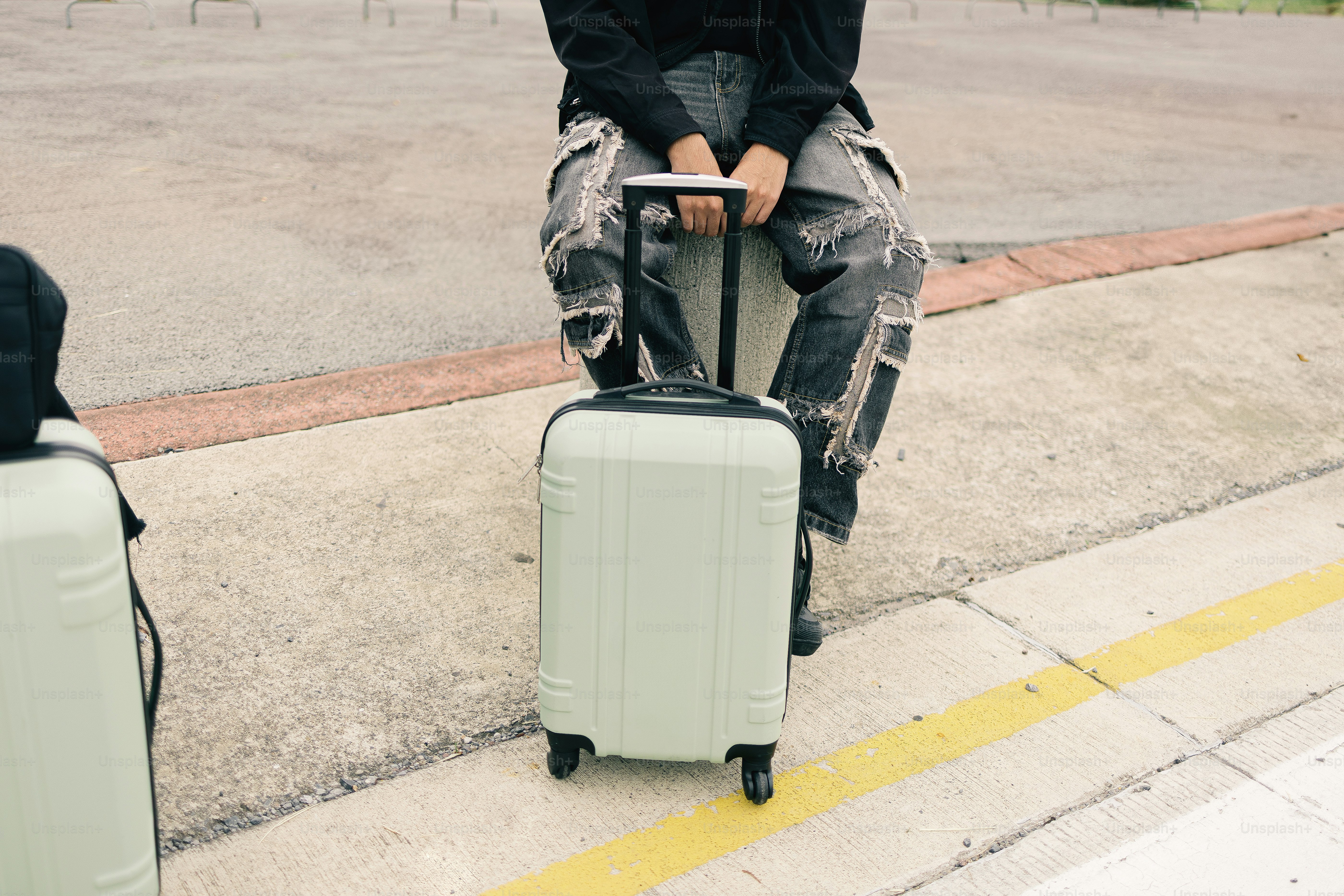 Person sitting with light green suitcase and luggage.