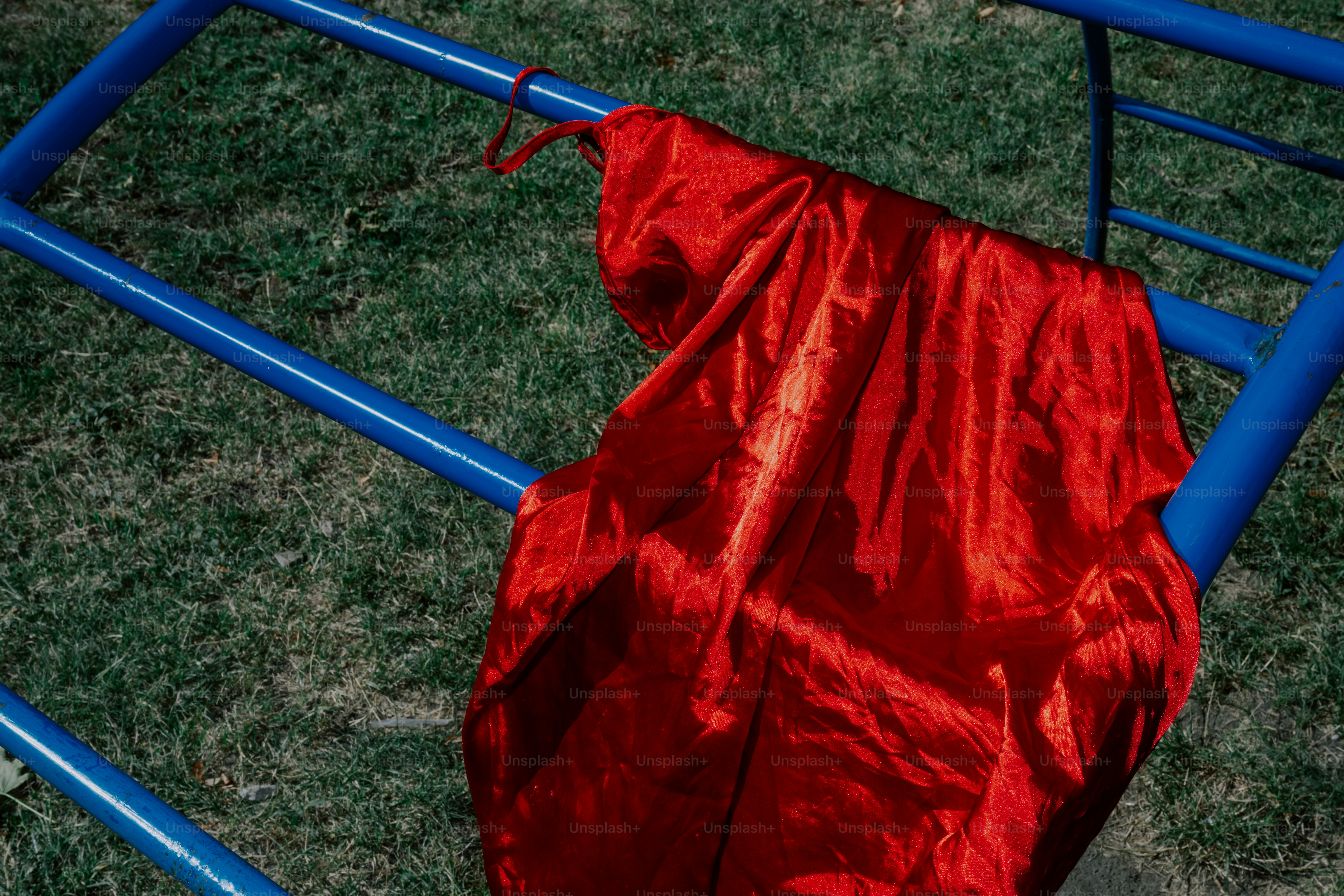 A shiny red fabric draped on blue bars.