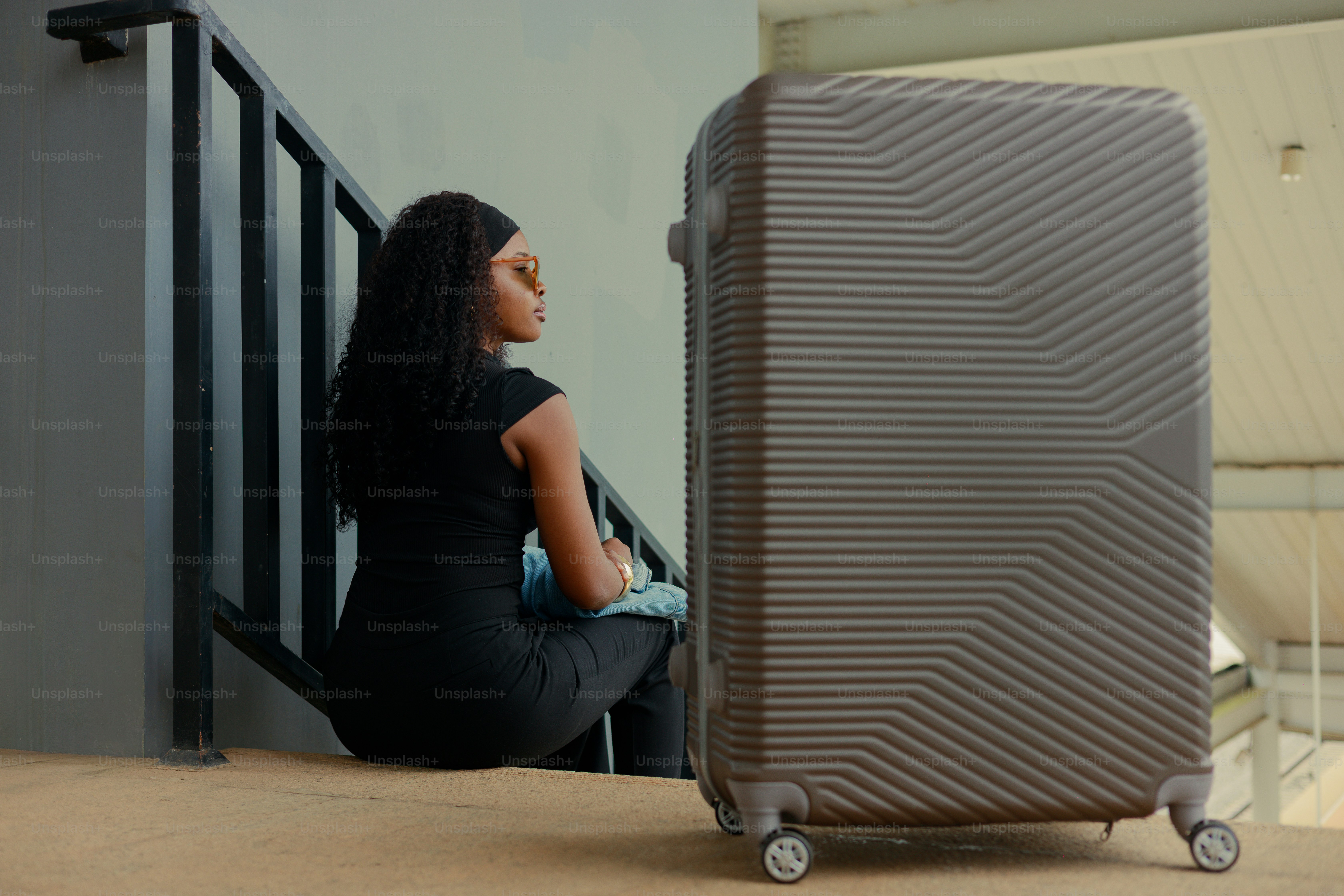 Woman sitting on stairs next to luggage