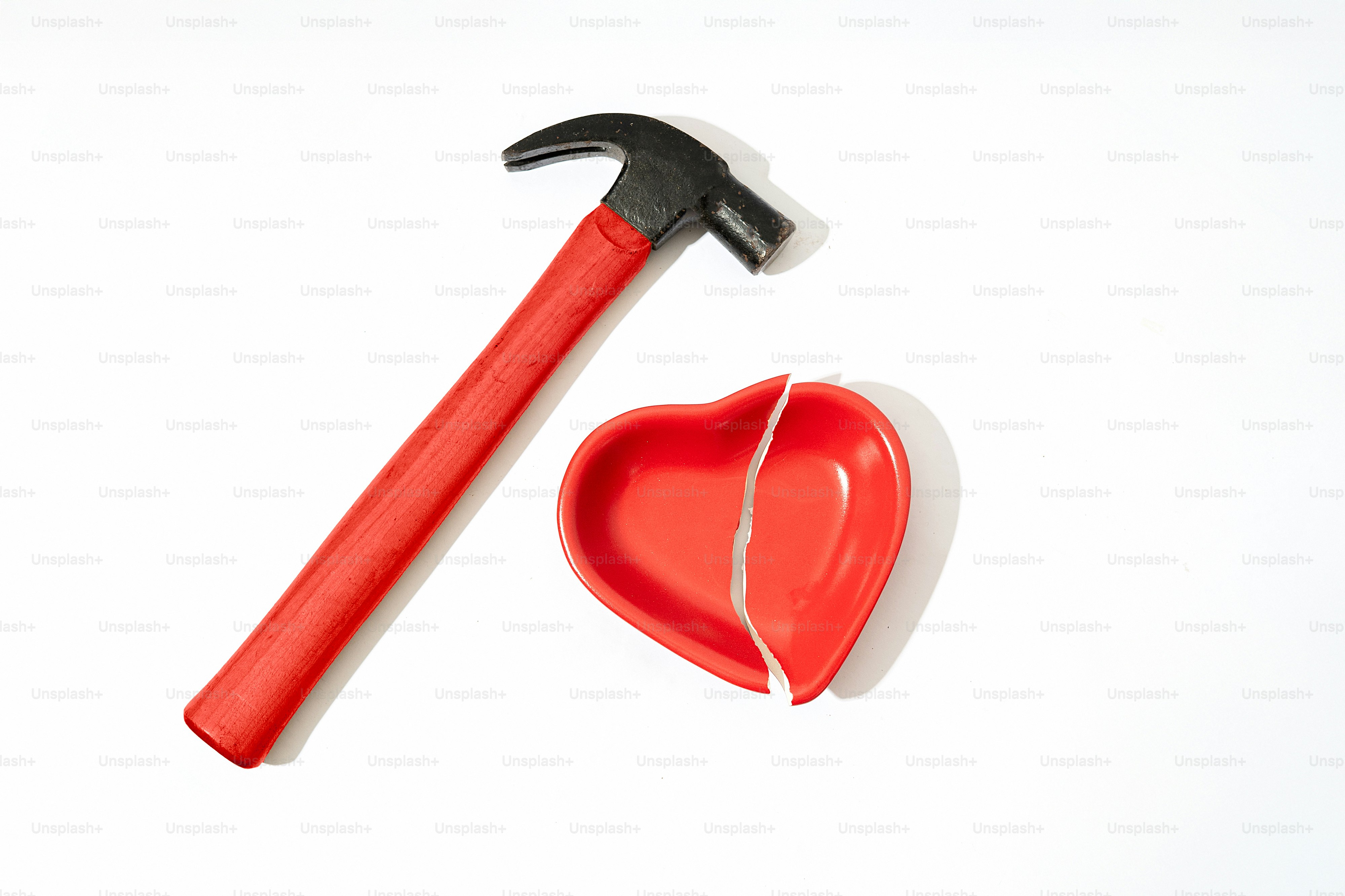 Hammer bricht ein rotes Herz auf weißem Hintergrund