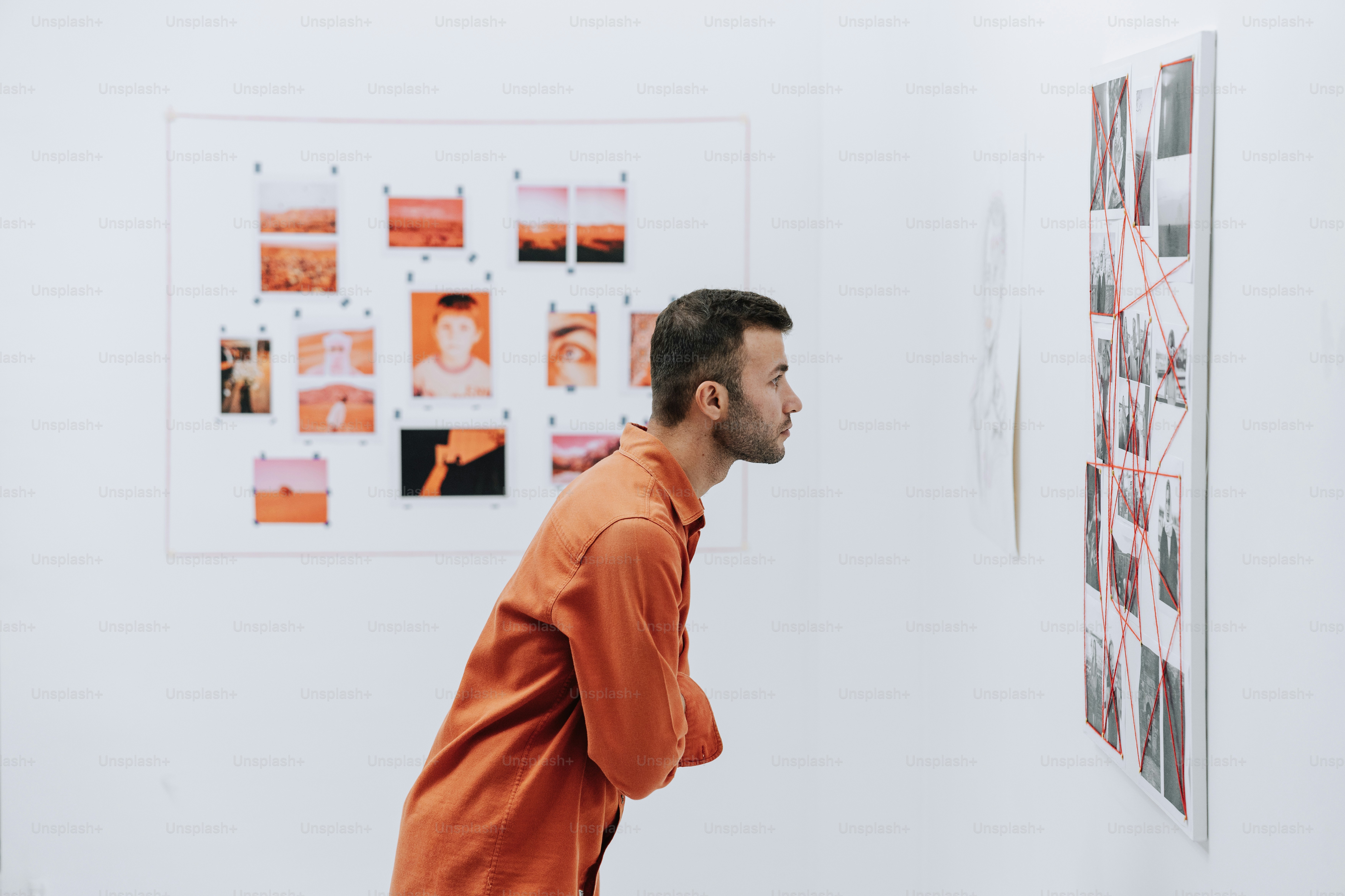 Man examining a collage of images on a wall.