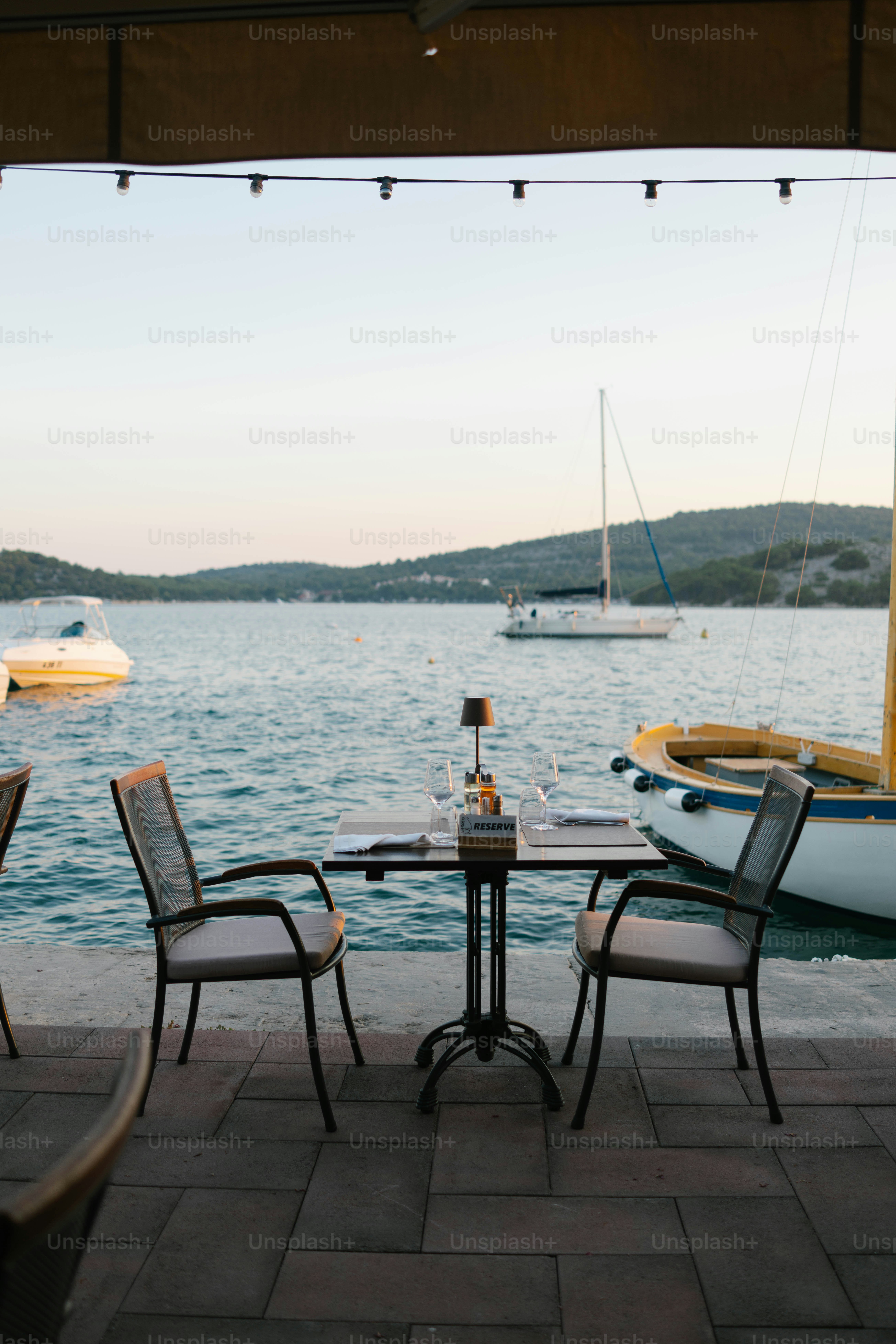 Two chairs at a table by the water