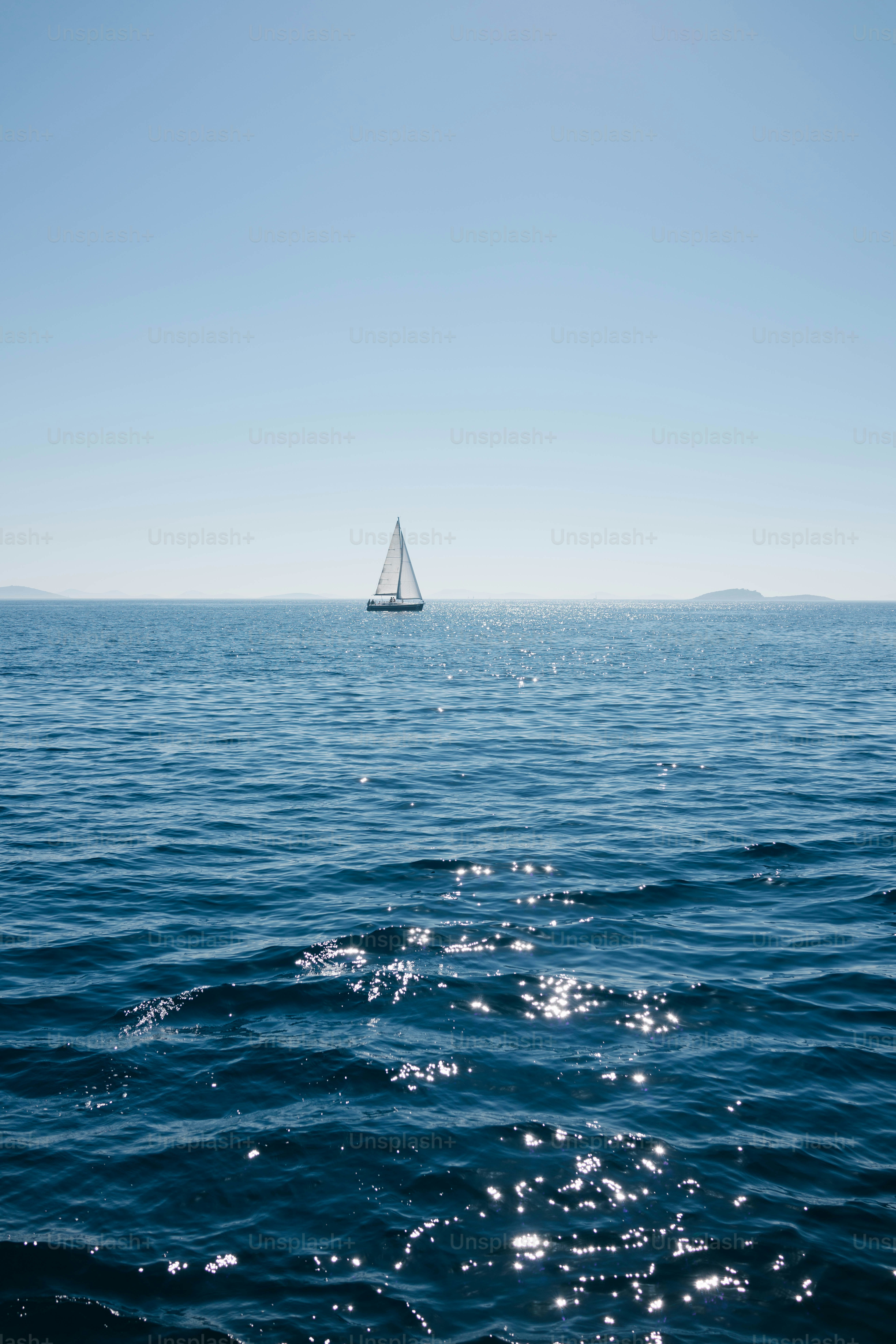 Sailboat on a calm blue ocean under clear sky