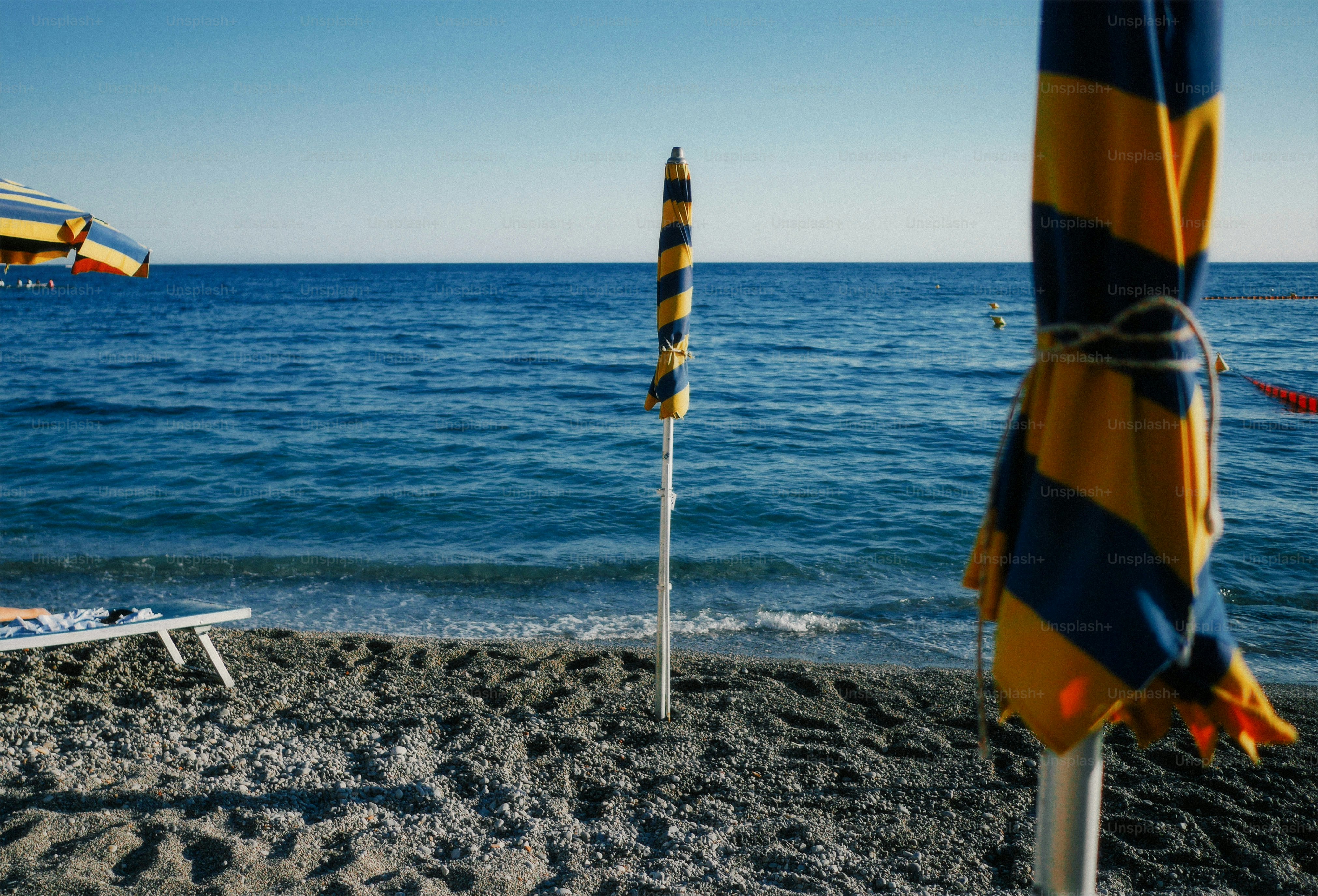 Beach umbrellas and lounge chair by the blue ocean.