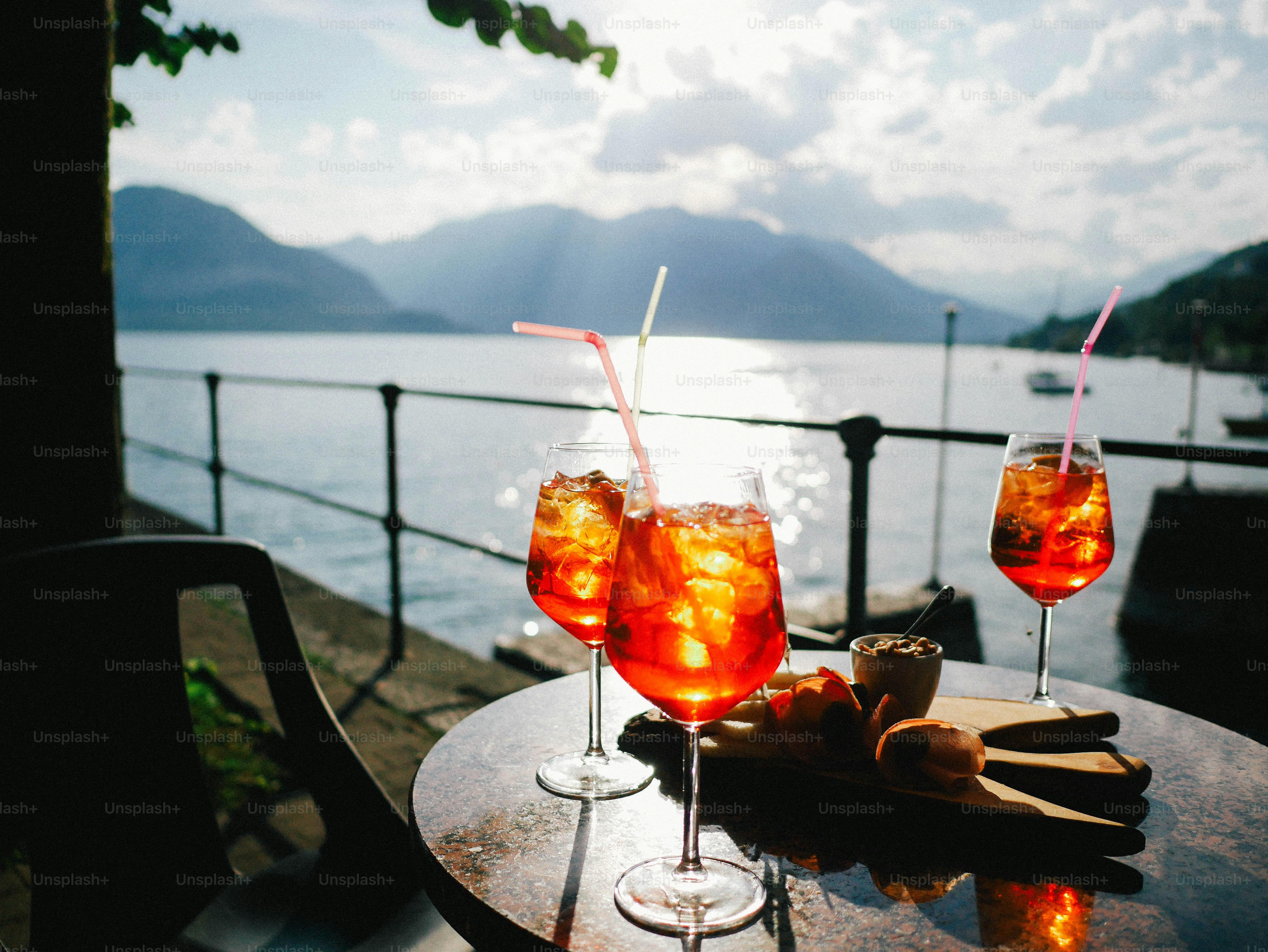 Three orange cocktails on a table by the lake.