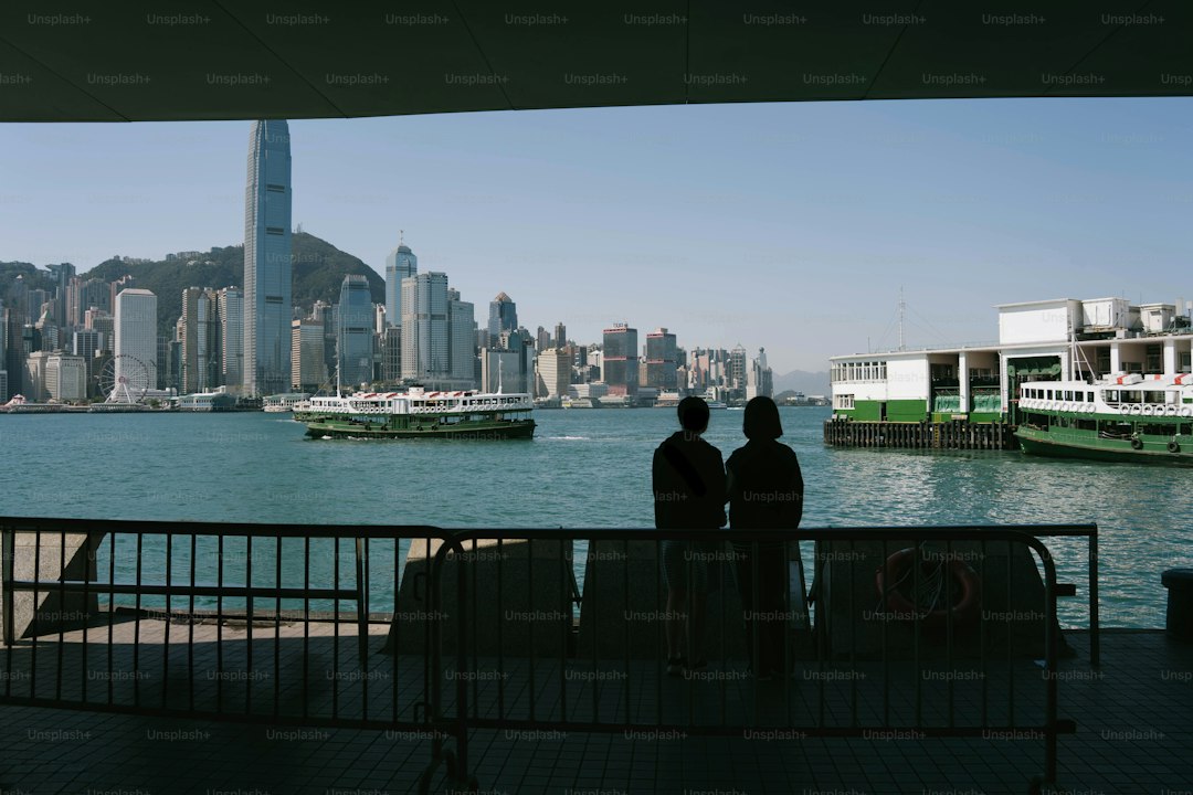 Two people watch hong kong skyline from a ferry.