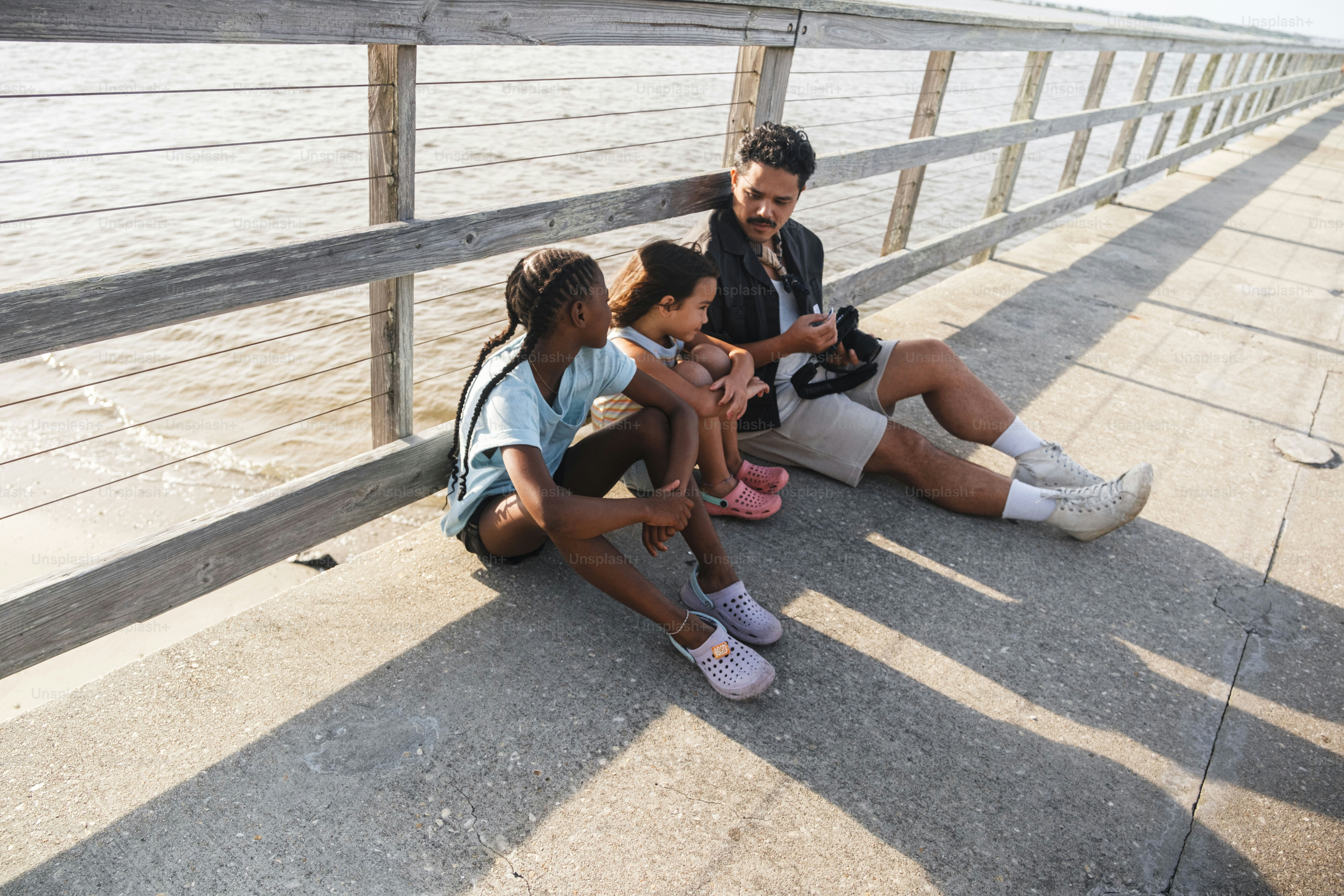 Father and daughters sitting on a pier