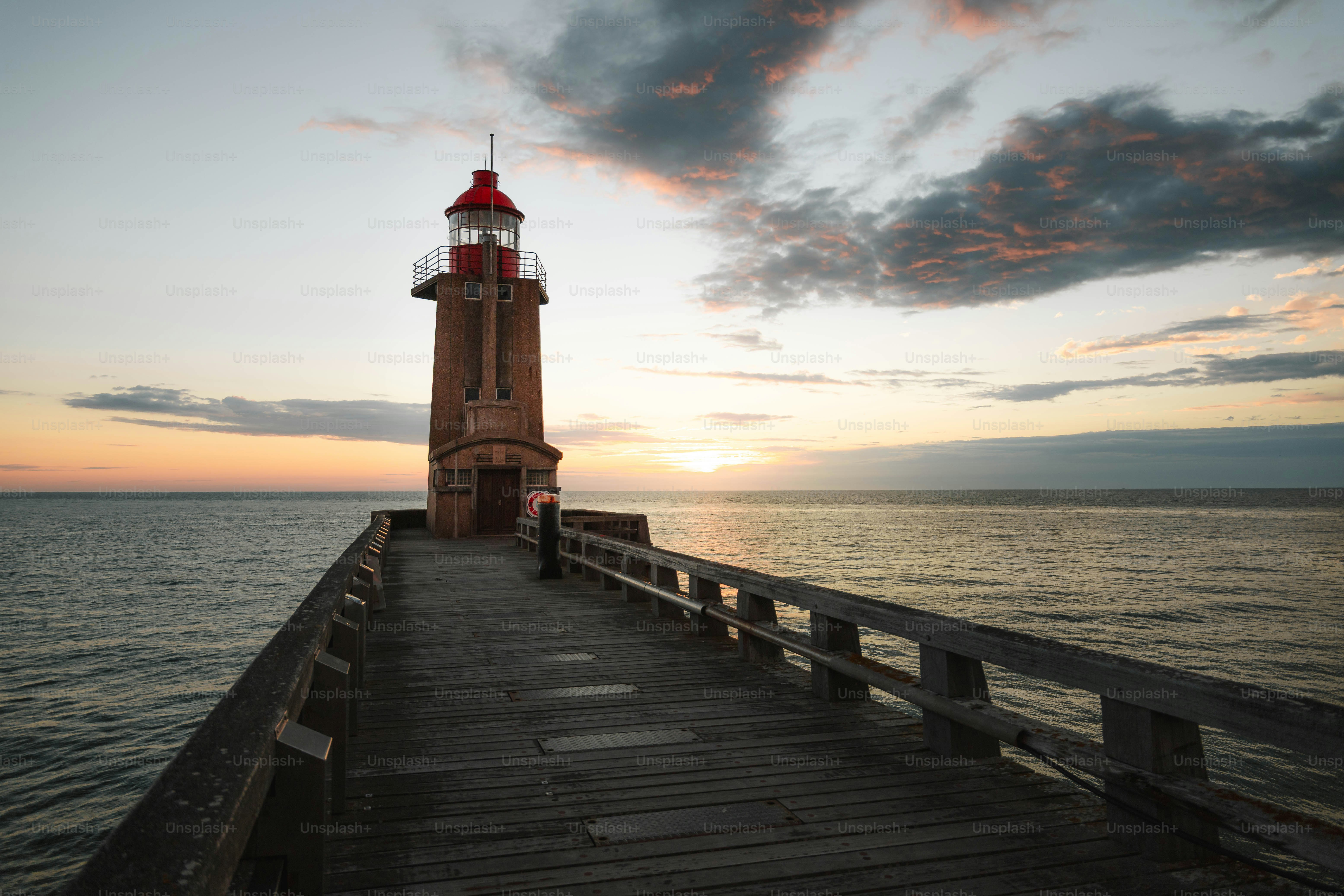 Lighthouse on a pier at sunset with clouds