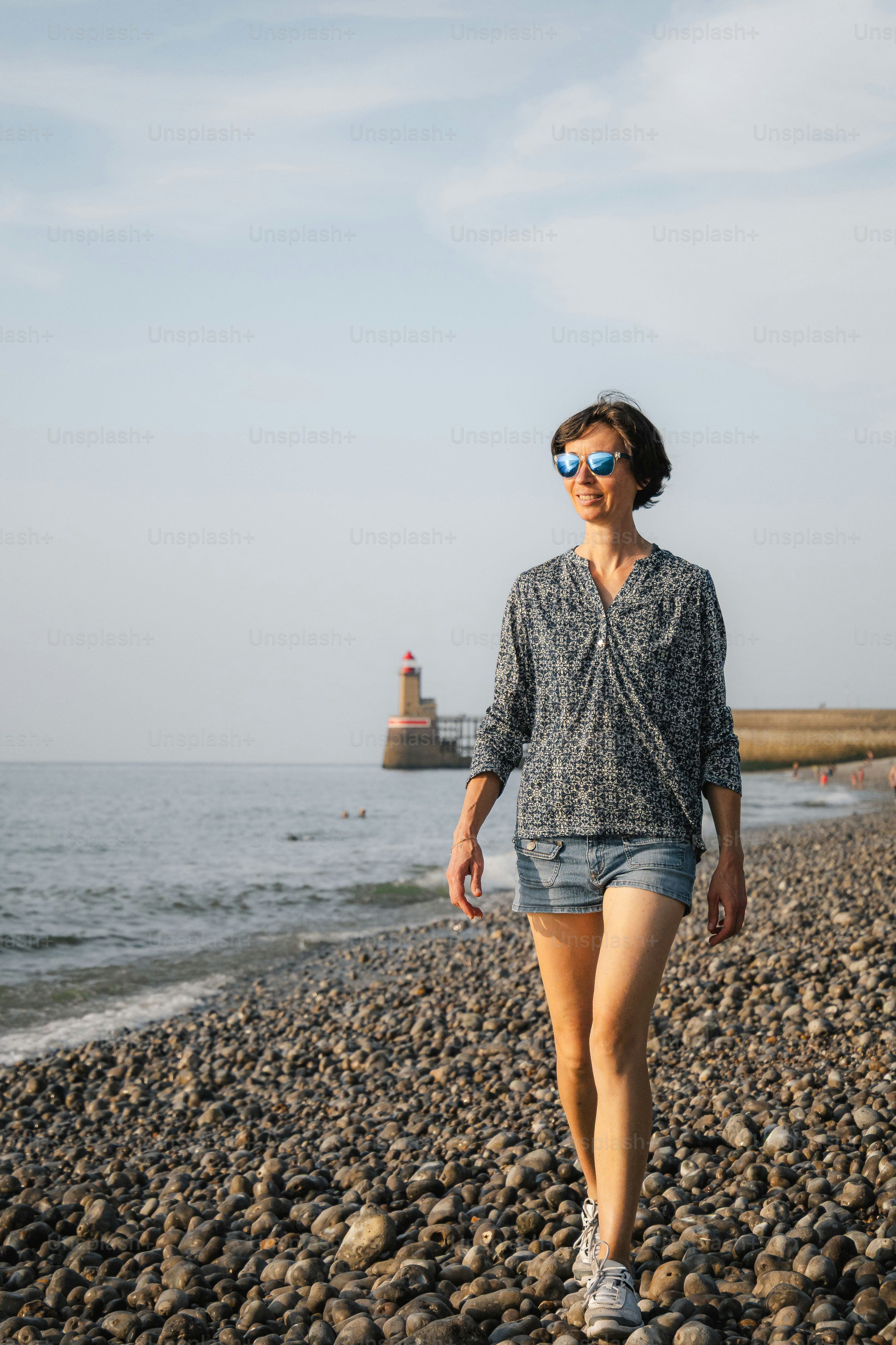 Woman walking on a pebble beach near the ocean.