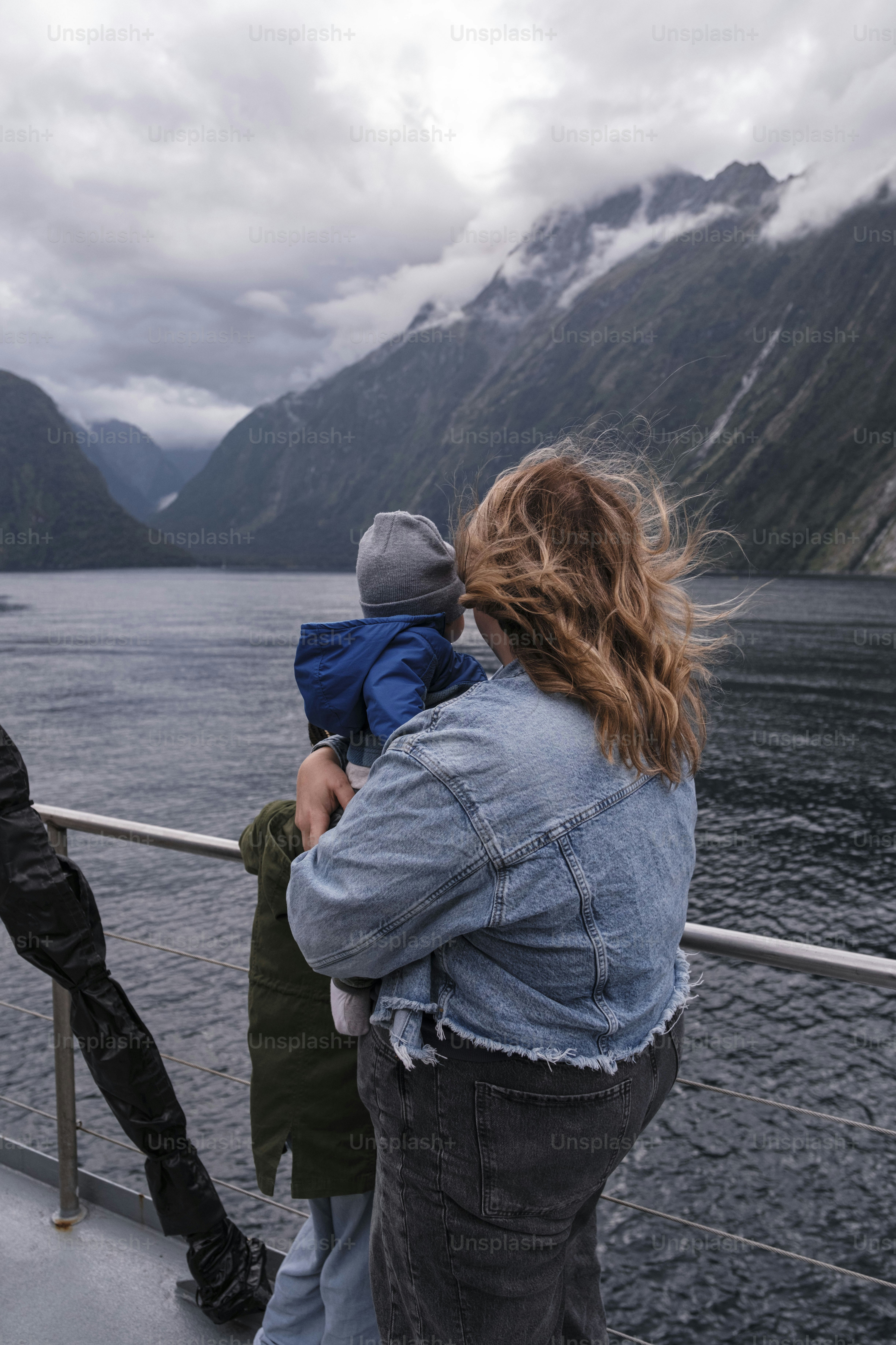 Mujer sosteniendo a un niño en un bote con vista a la montaña