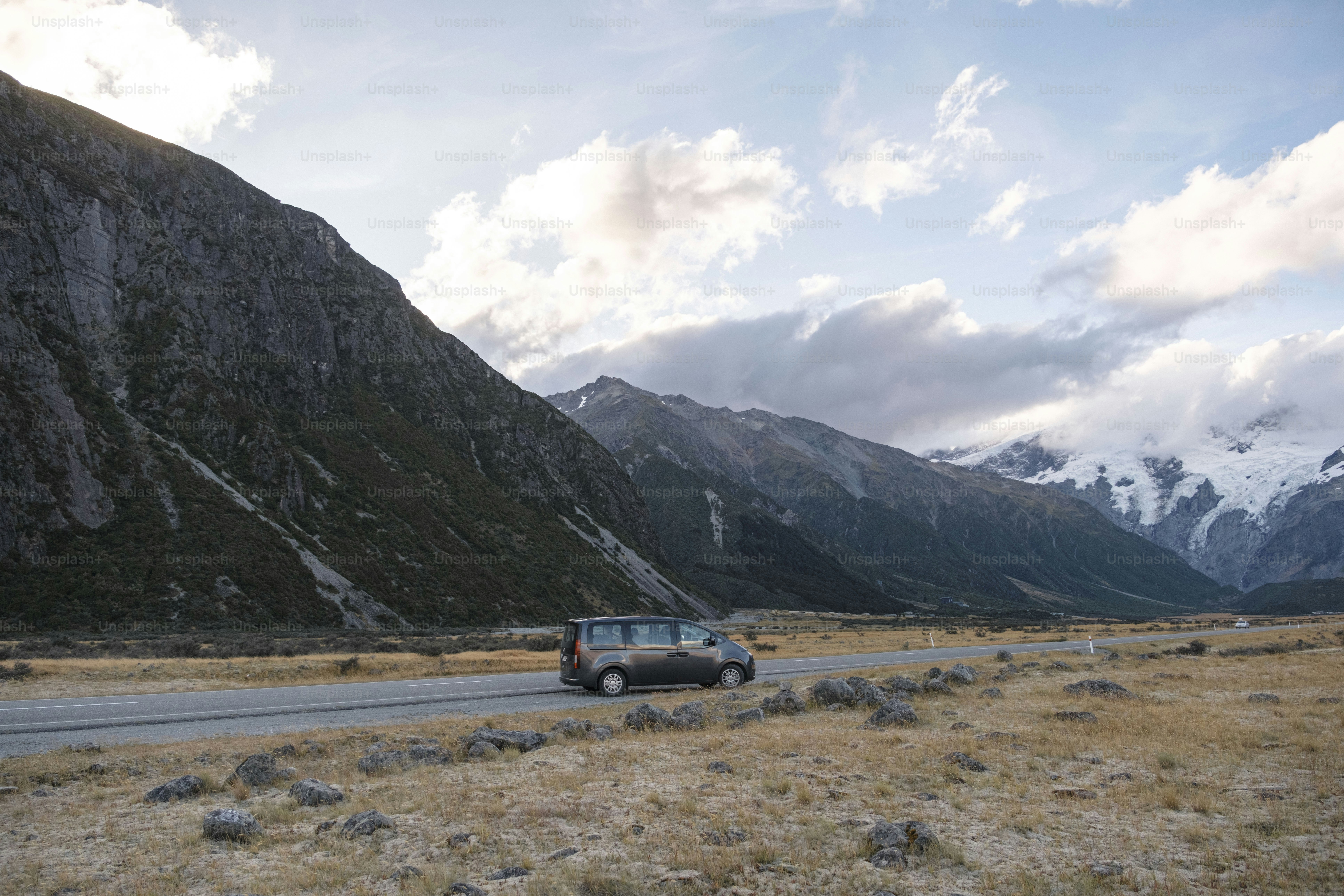Van driving on road towards snow-capped mountains