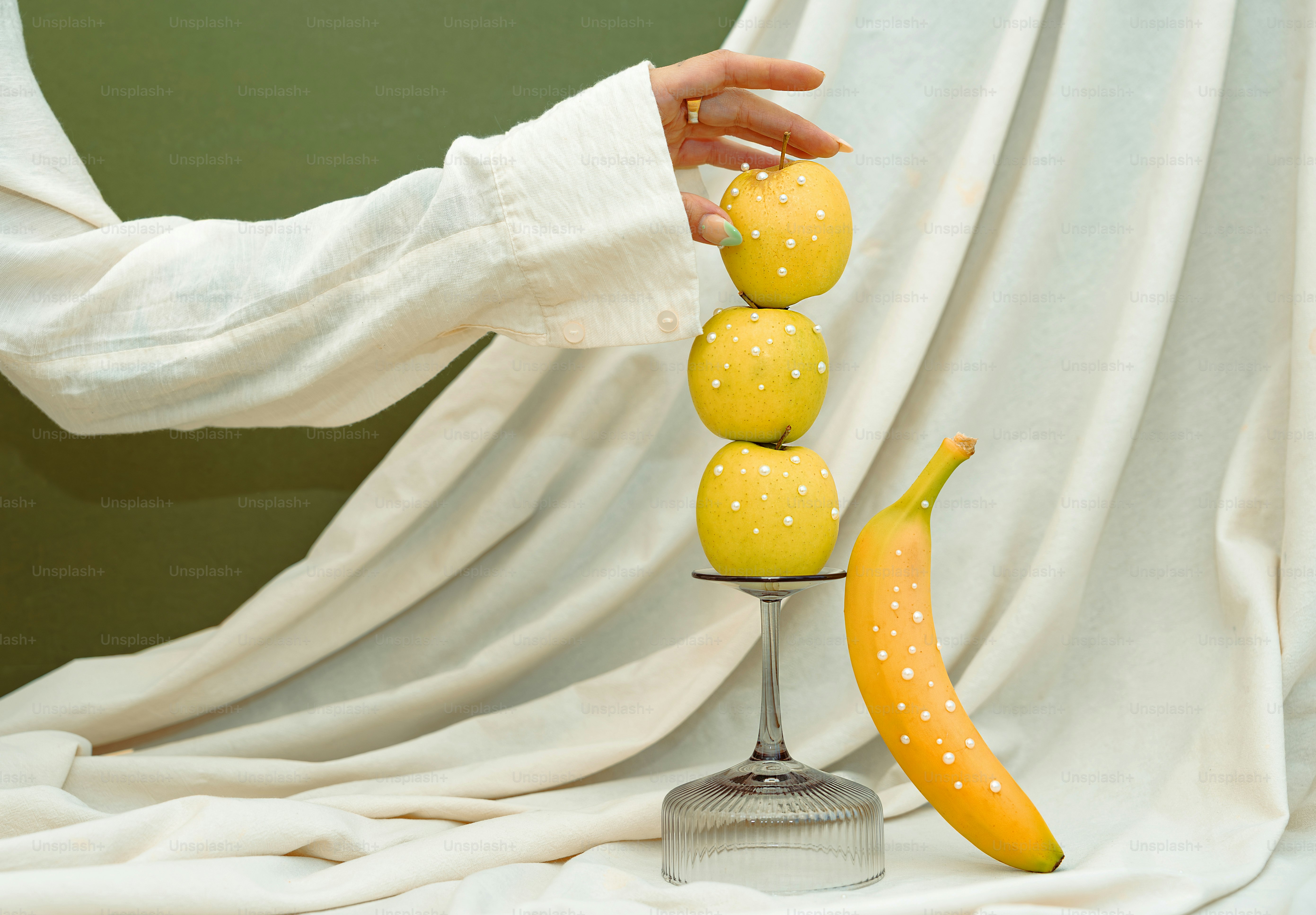 Hand stacking yellow apples with white dots