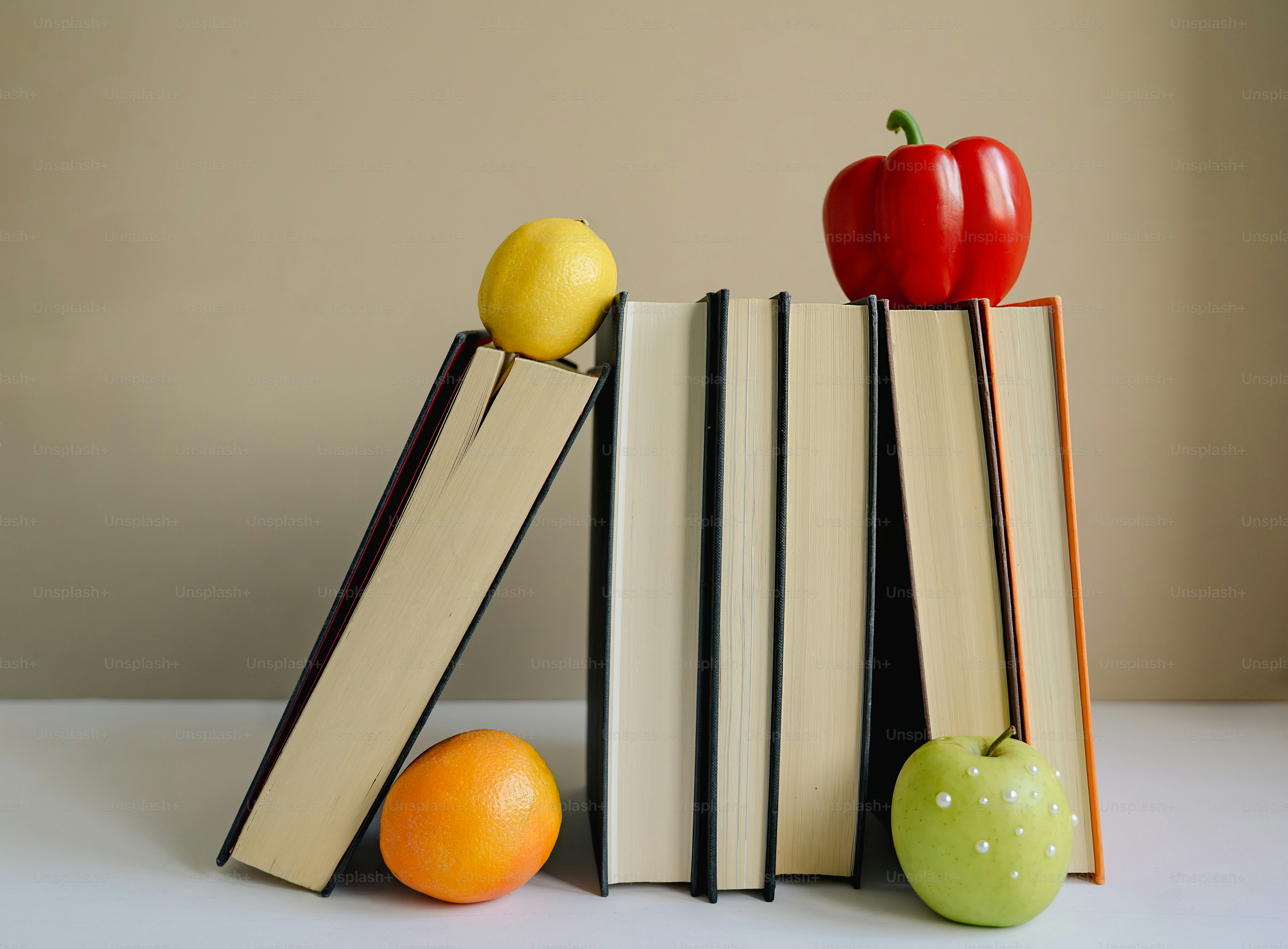 Books with fruits and a red pepper arranged