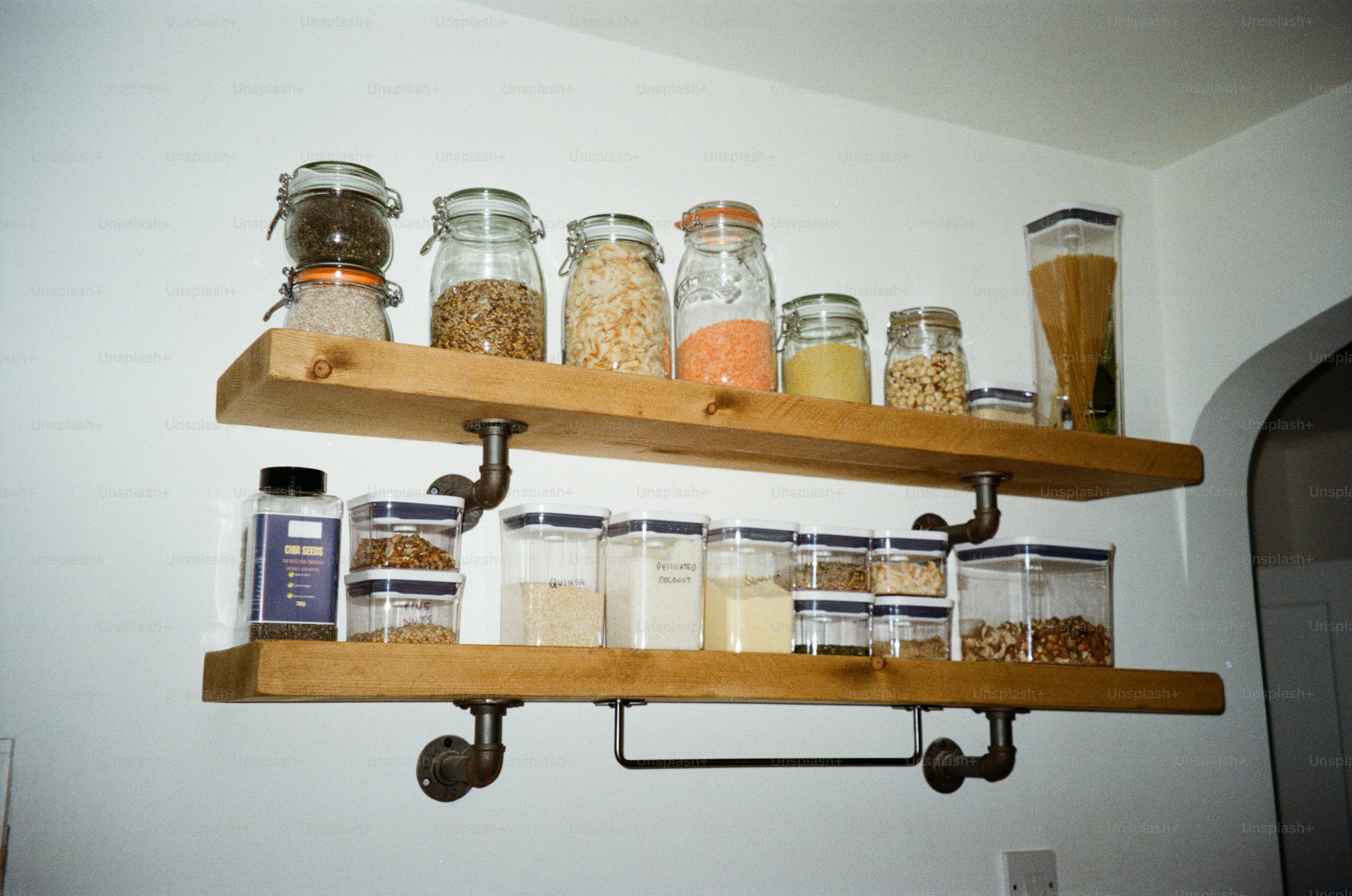 Neatly arranged glass storage jars filled with pantry staples on open kitchen shelves