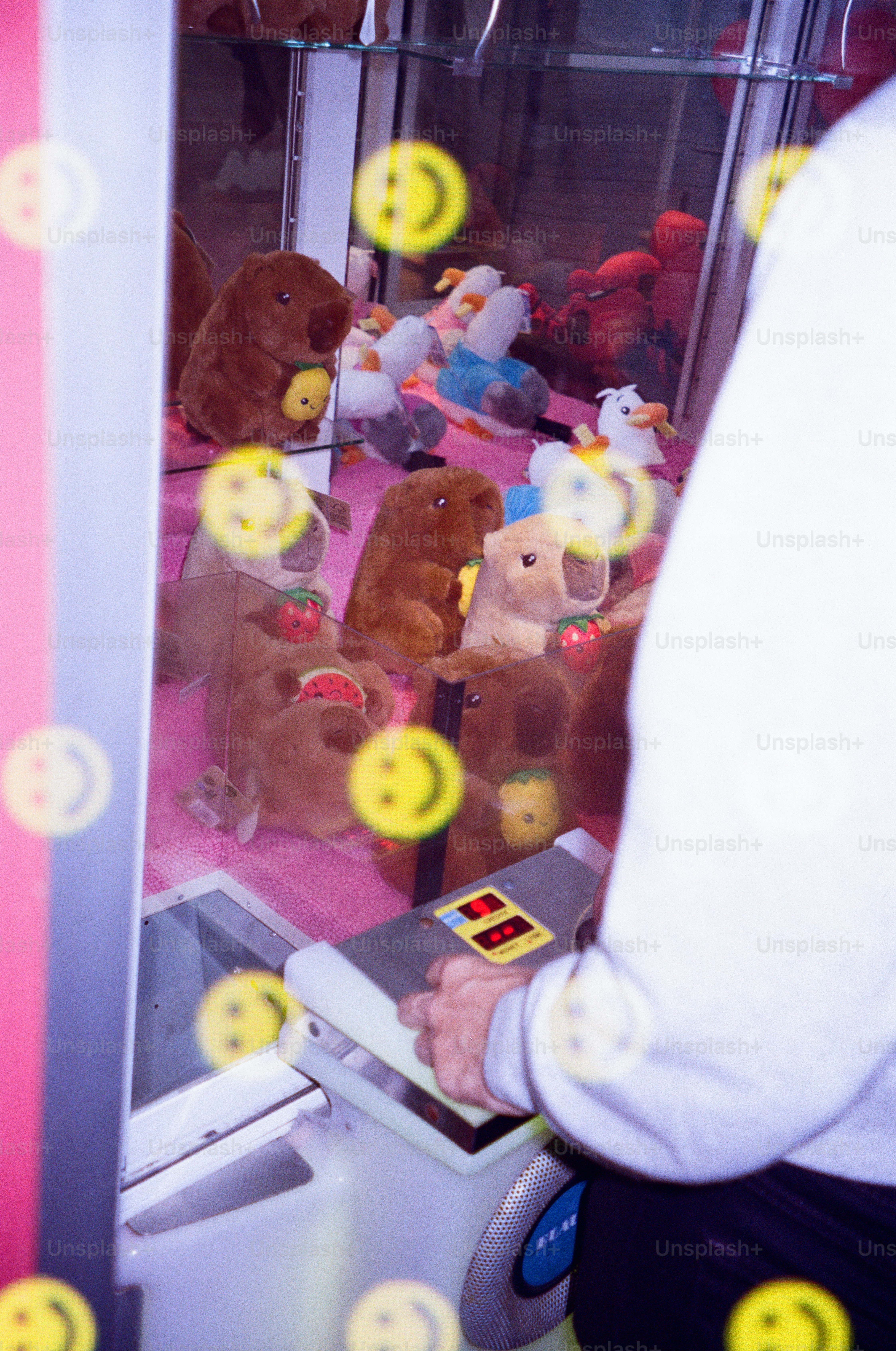 Person playing a plush toy claw machine game.