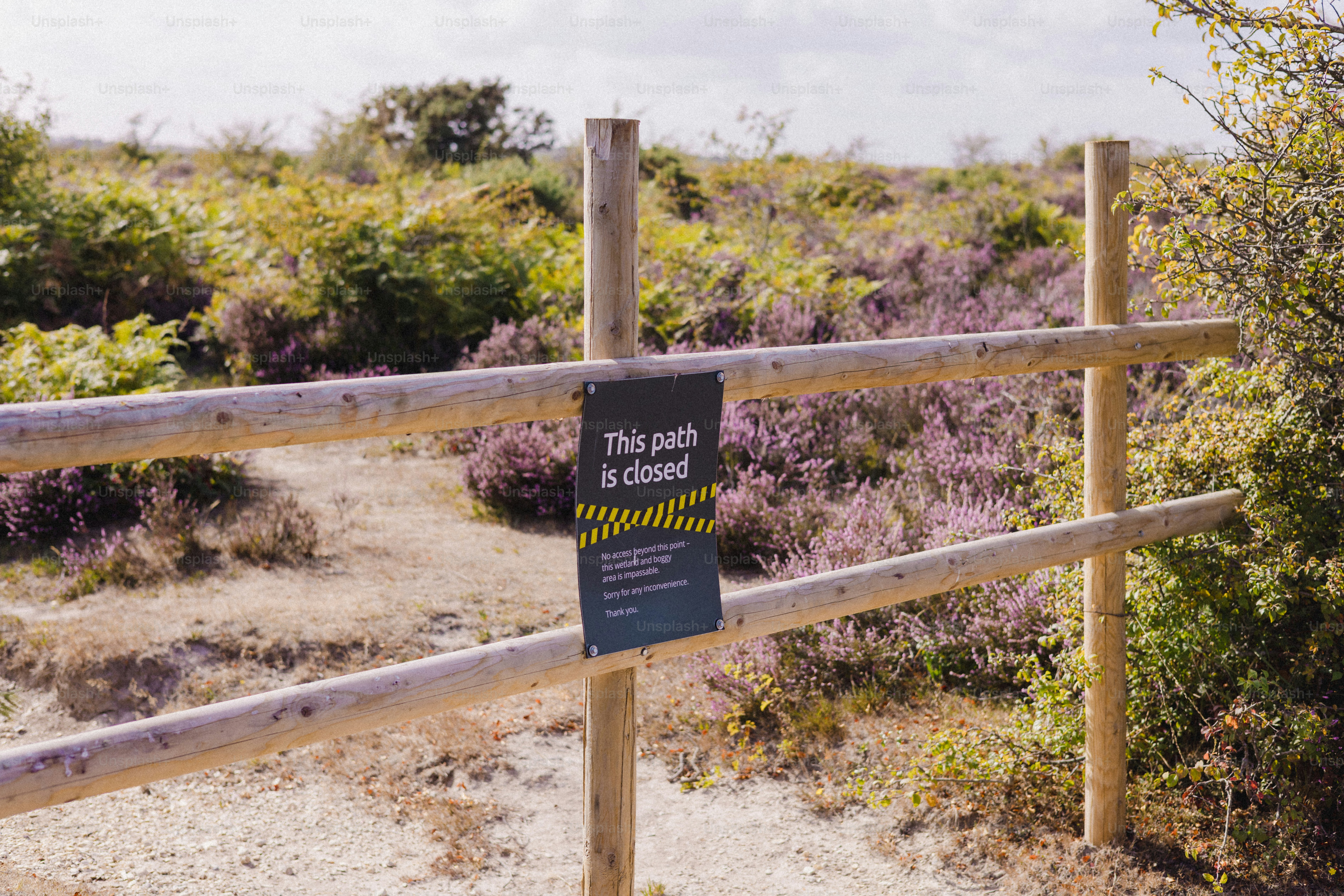 Wooden fence with a closed path sign in a heathland.