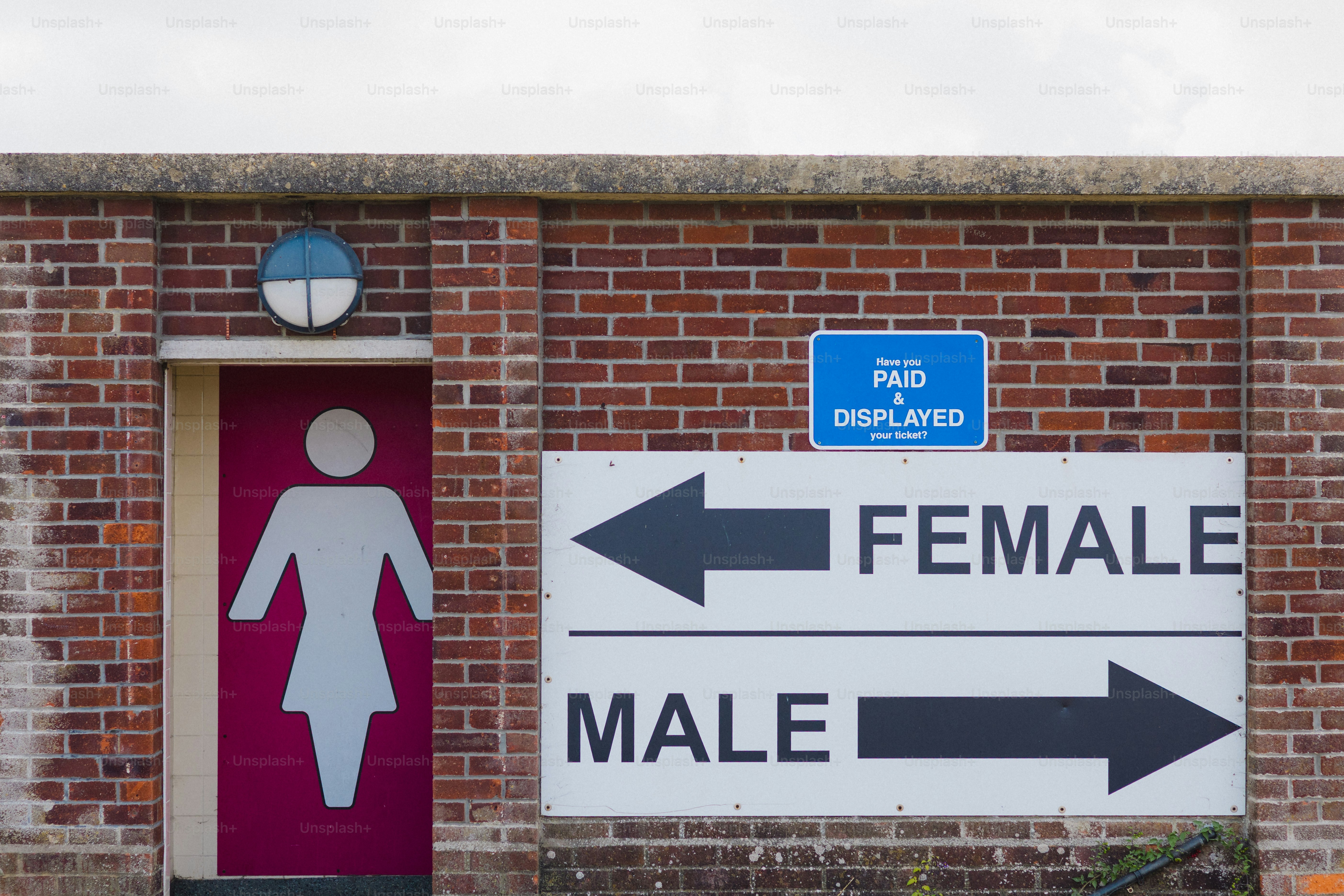 Female and male restroom signs on brick wall.